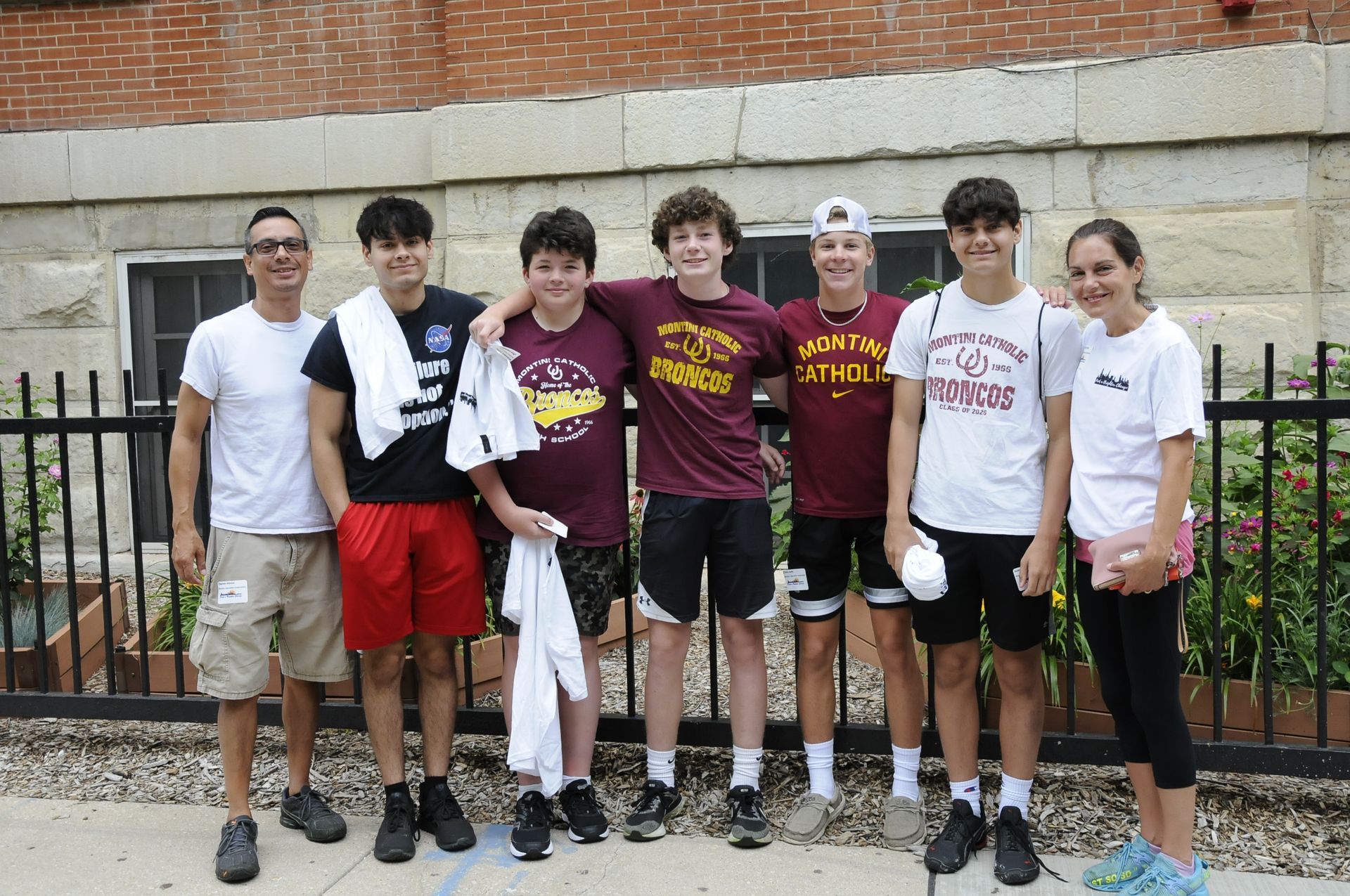 A group of young people are posing for a picture in front of a fence.