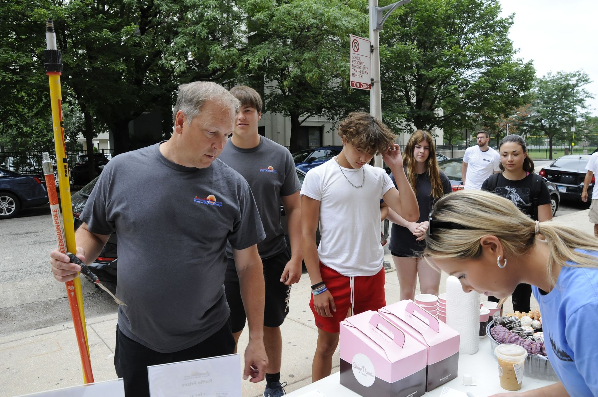 A group of people are standing around a table with cupcakes on it.