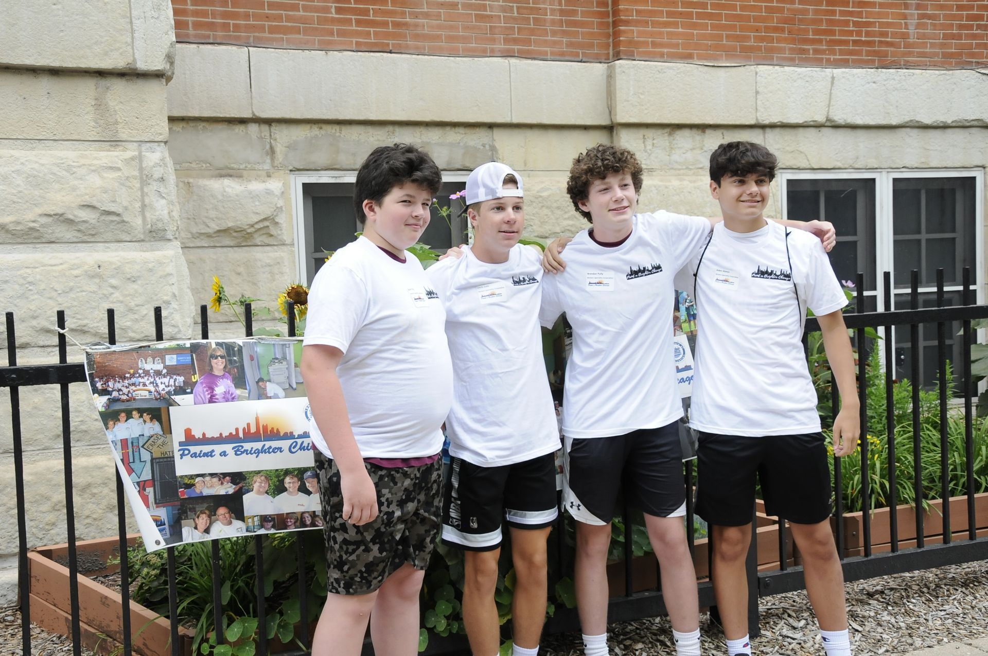 A group of young men are posing for a picture in front of a brick building.