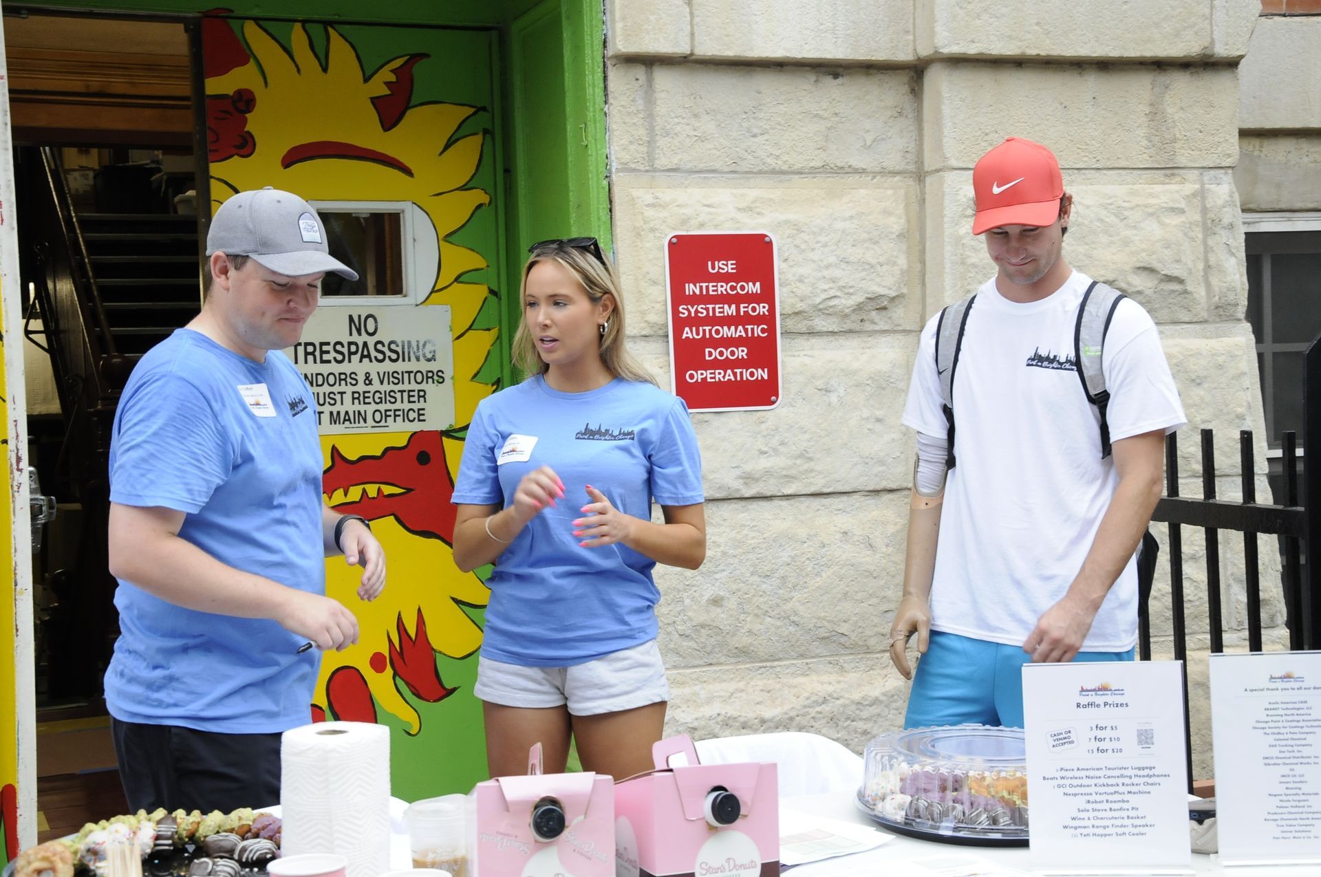 A group of people standing around a table in front of a sign that says no pets
