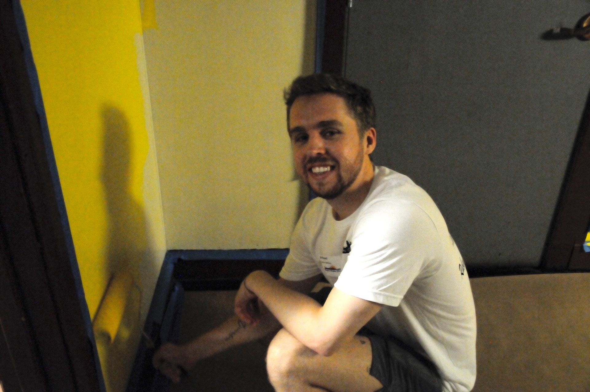 A man in a white shirt is sitting on the floor in a room.