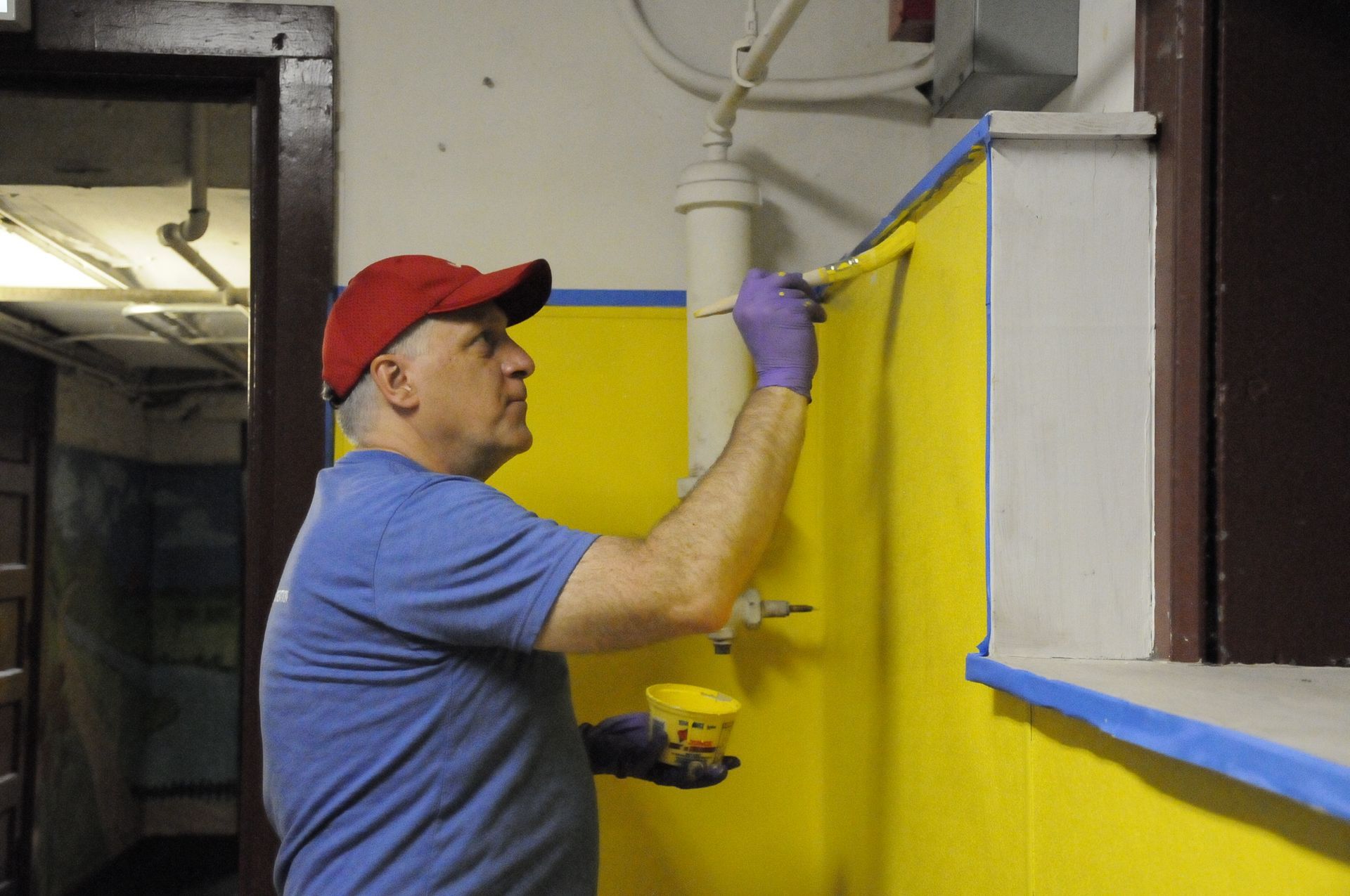 A man is painting a yellow wall with a brush