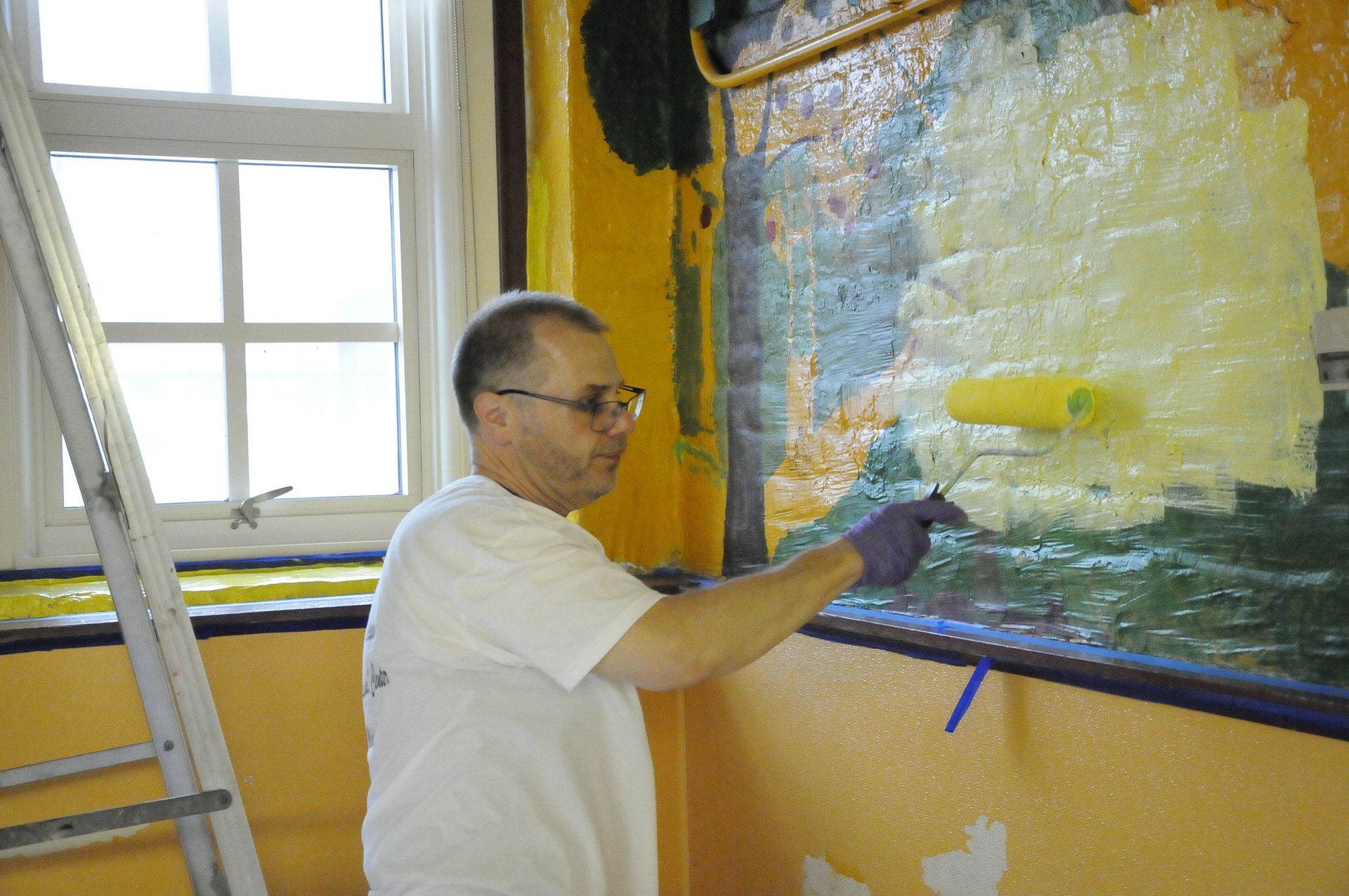 A man is painting a wall with a roller.