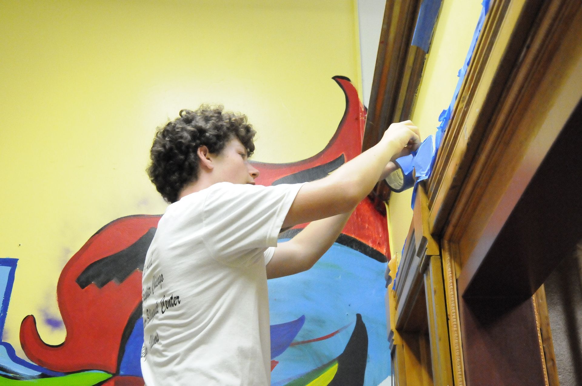 A young man is painting a mural on a wall