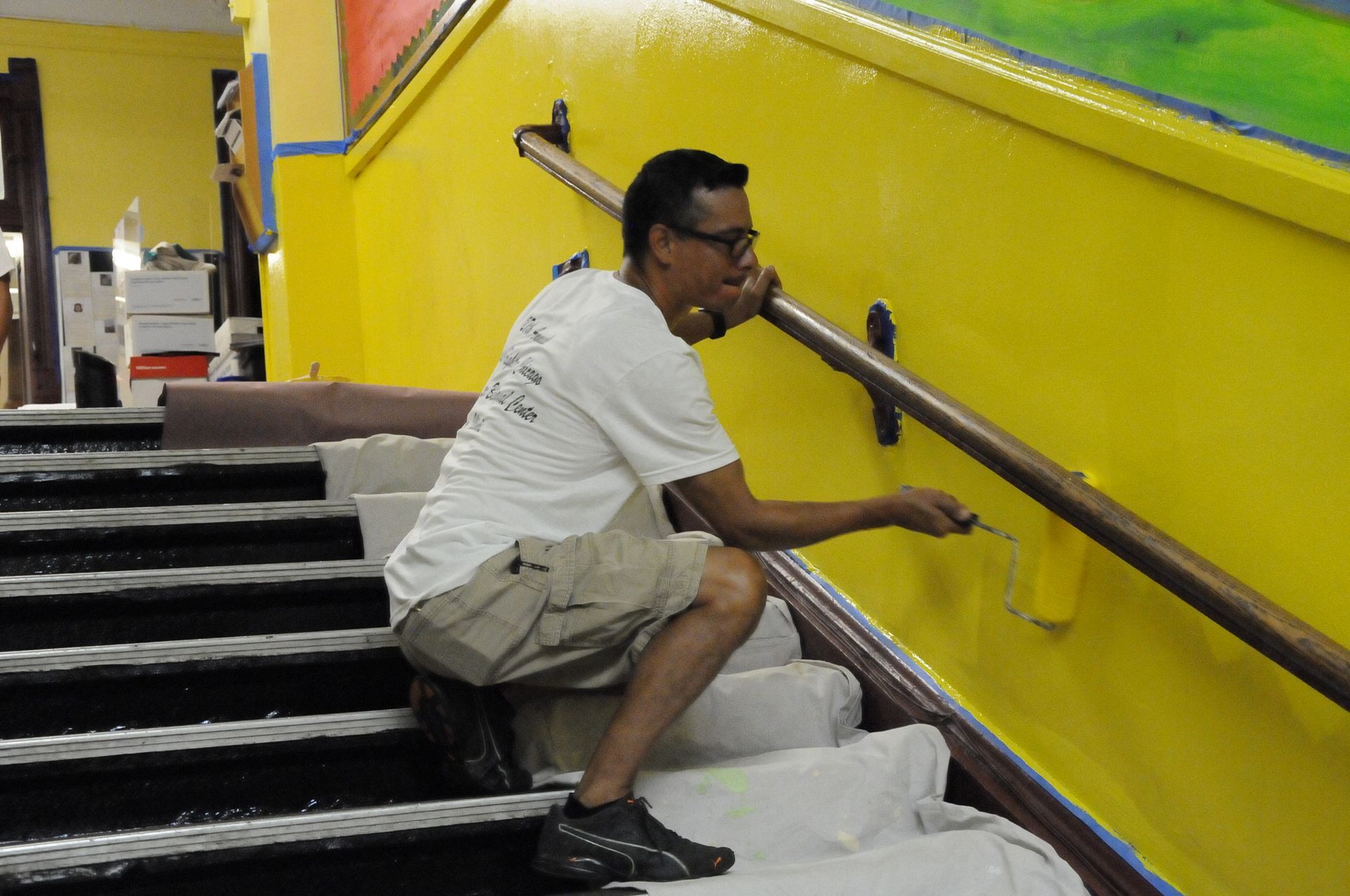 A man is painting a yellow wall with a brush