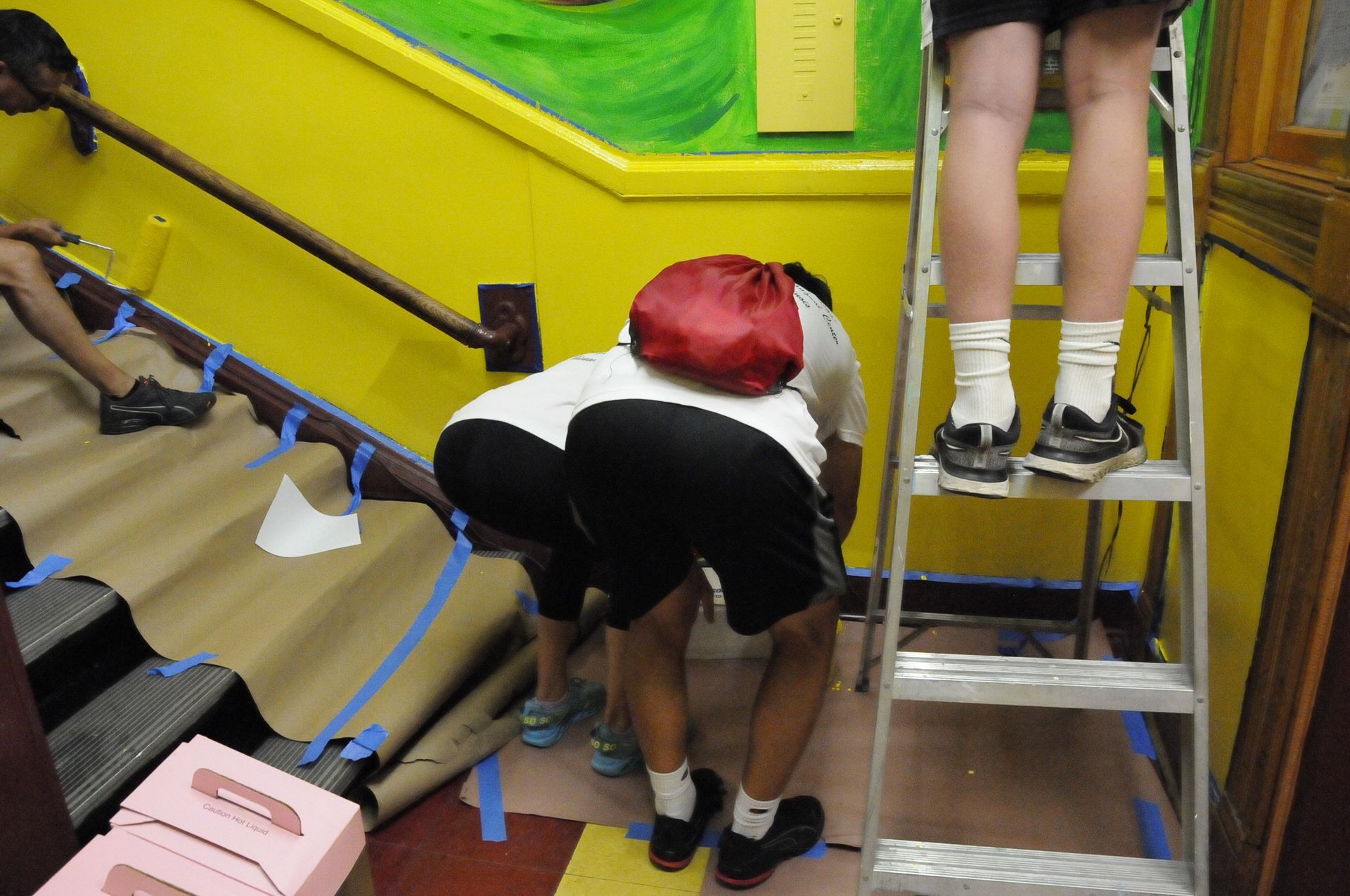 A person on a ladder with a red bag on their back