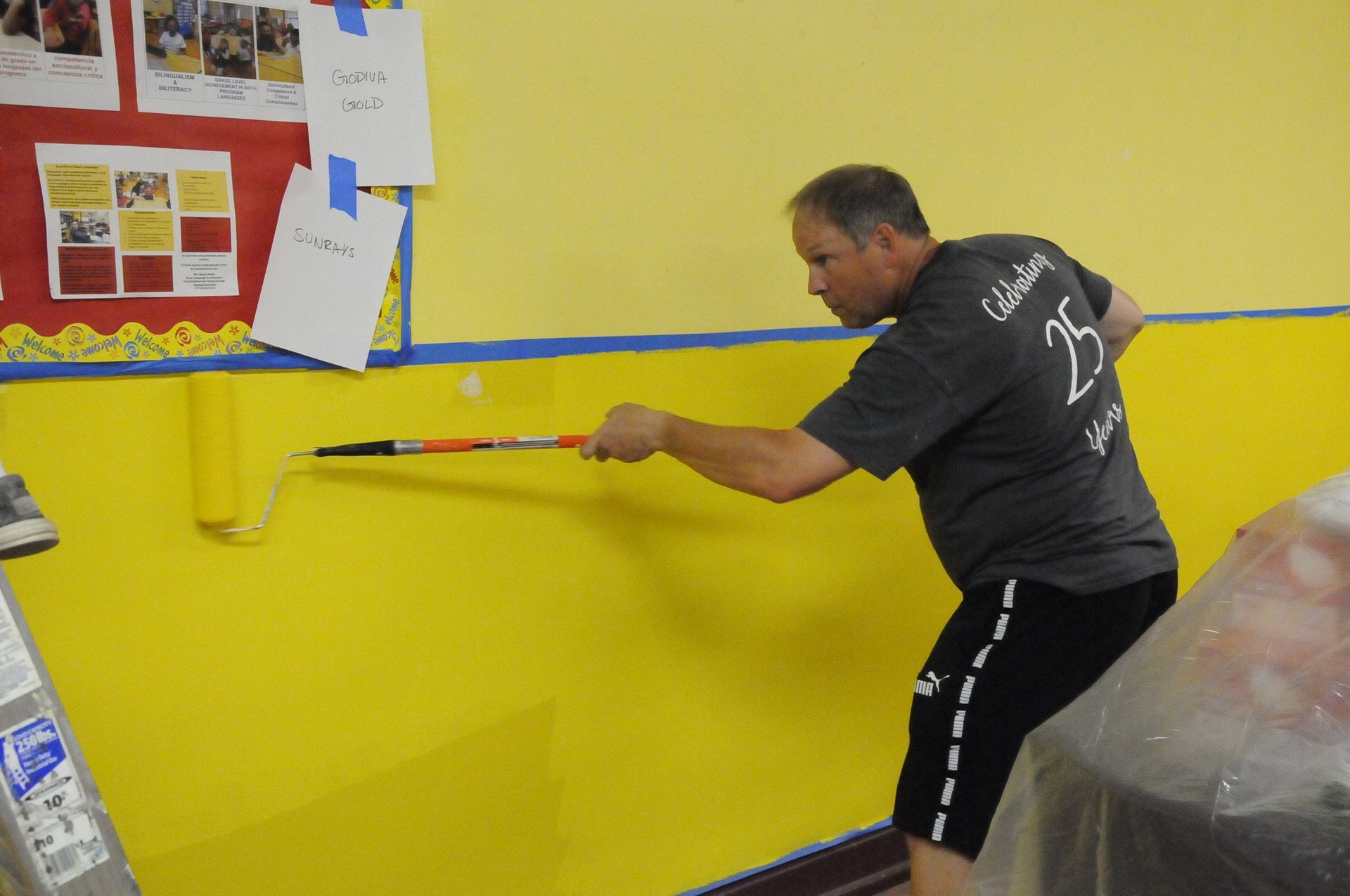 A man is painting a yellow wall with a paint roller