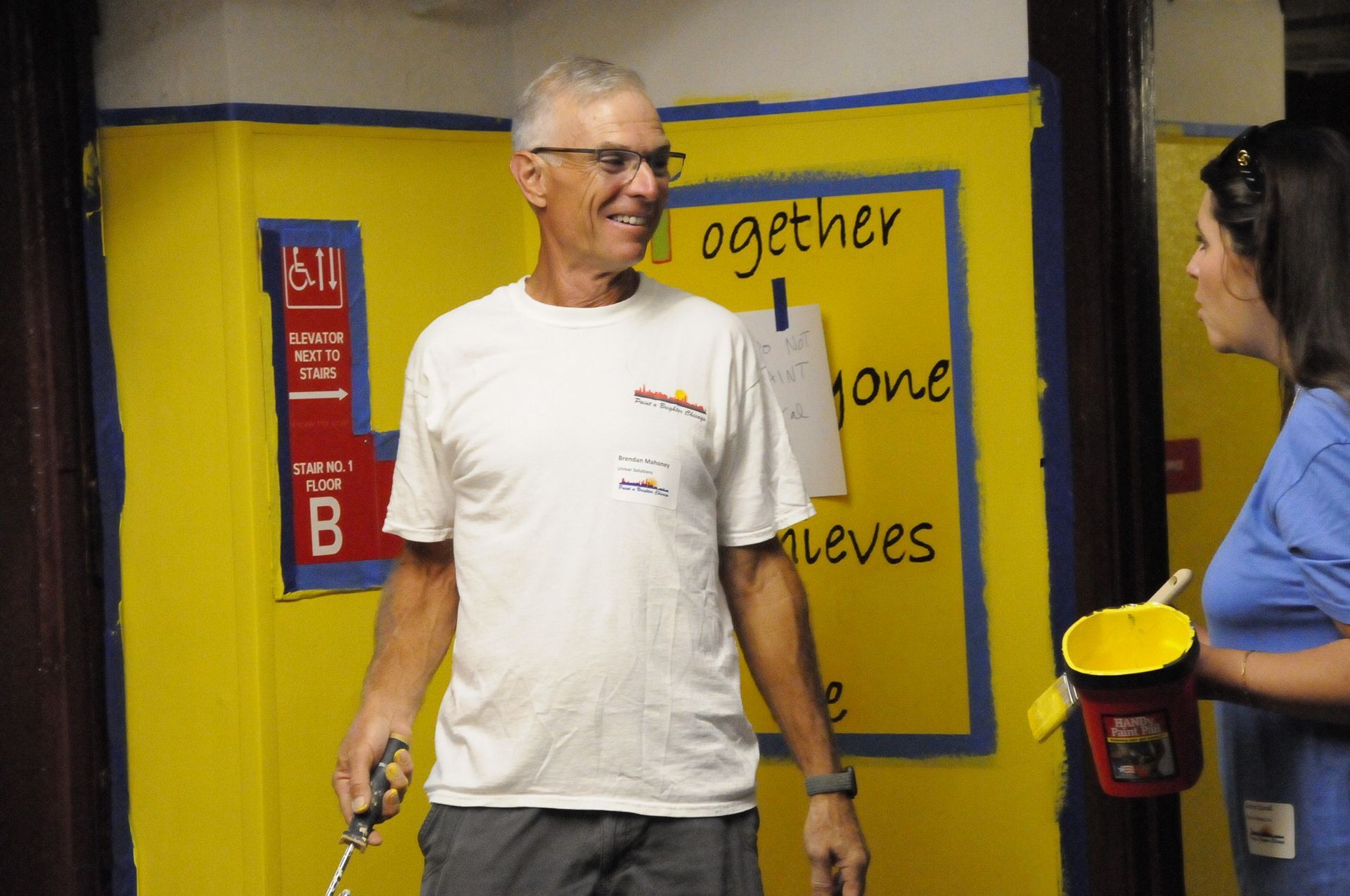 A man and a woman are standing in front of a sign that says together one achieves