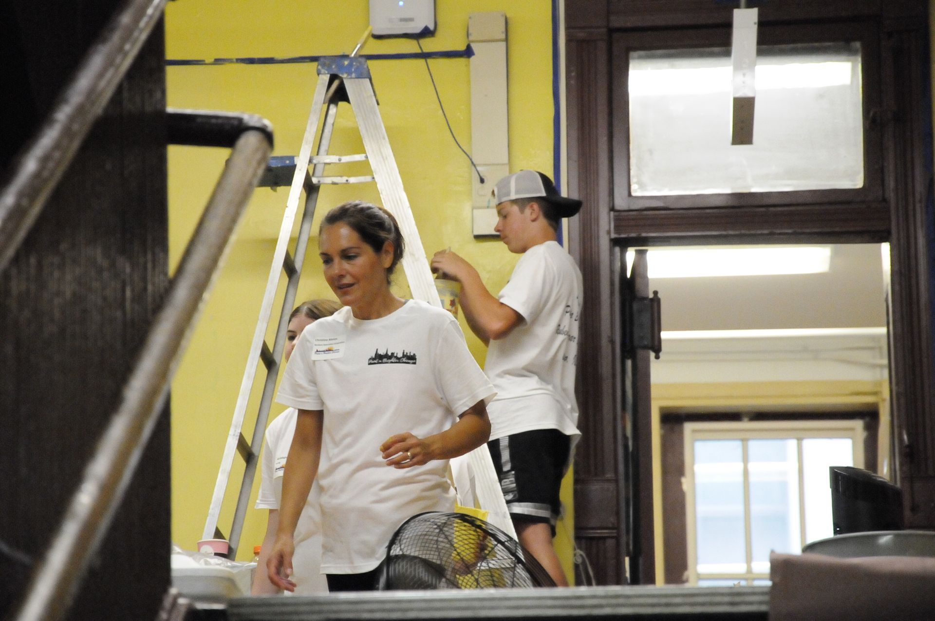 A man and a woman are painting a yellow wall