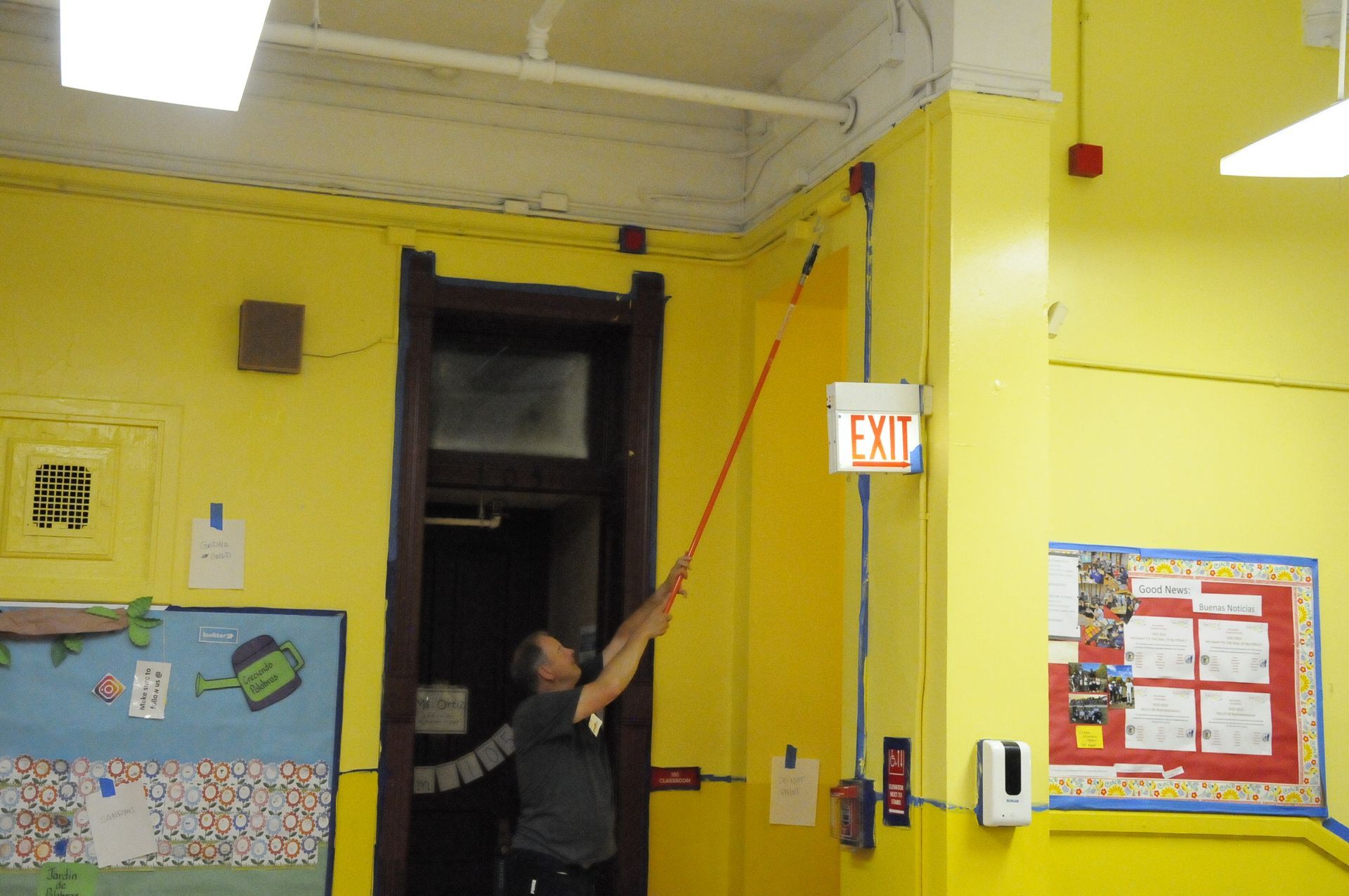 A man is reaching up to a red exit sign