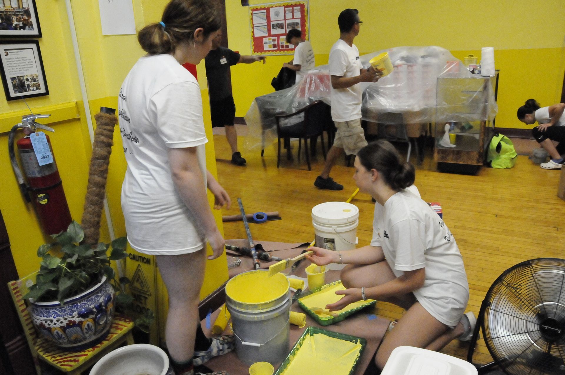 A group of people are painting a wall with yellow paint