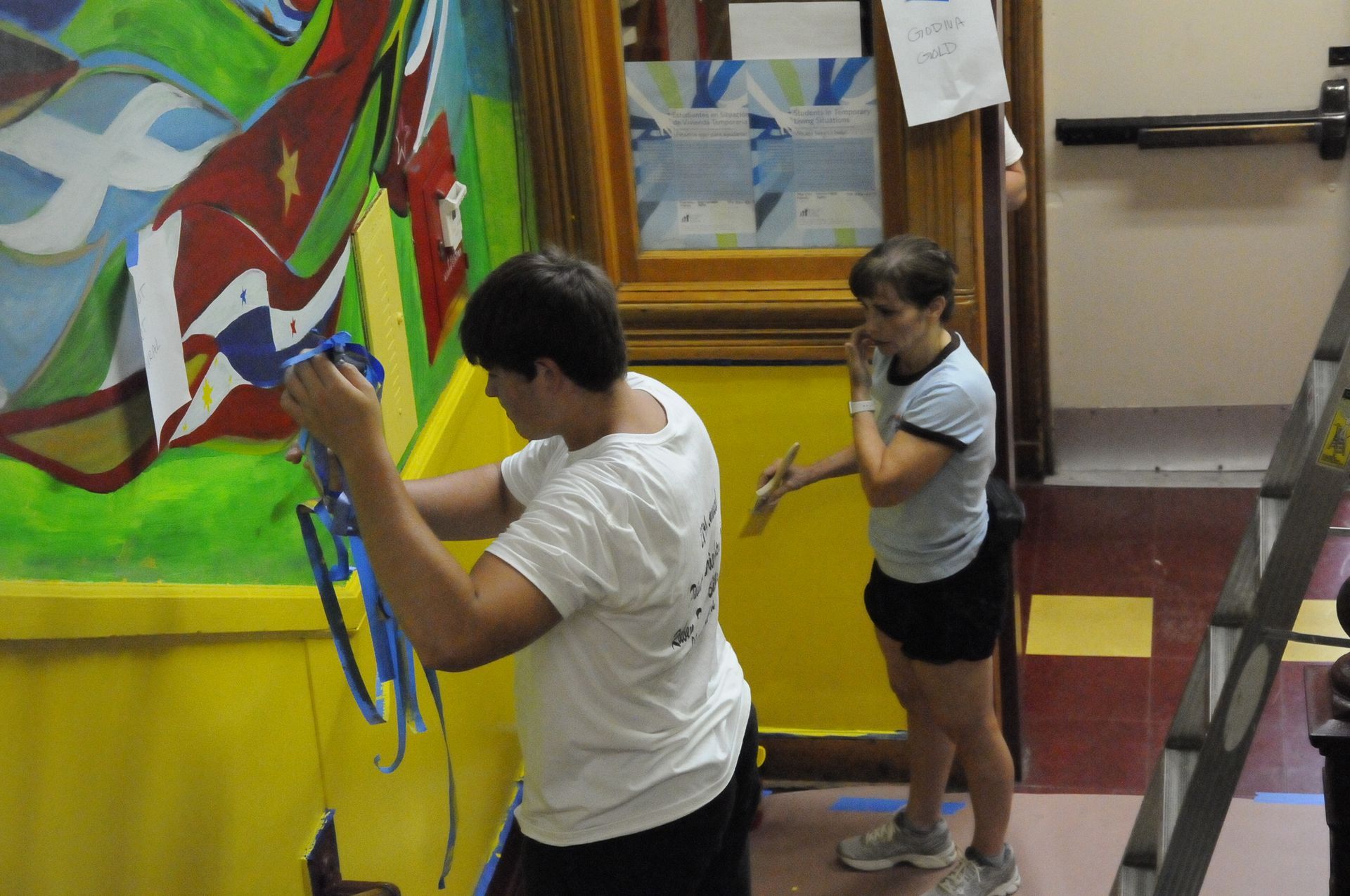 Two women are working on a mural on a wall