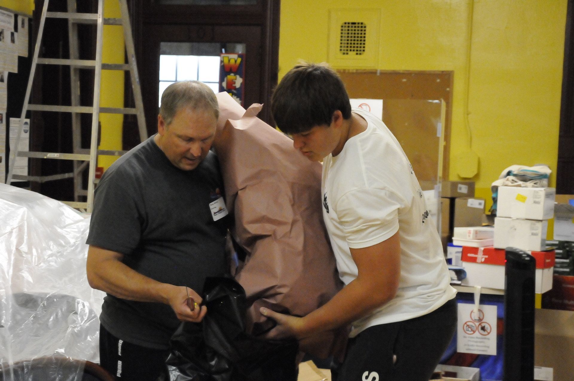 Two men standing next to each other with one wearing a shirt that says us