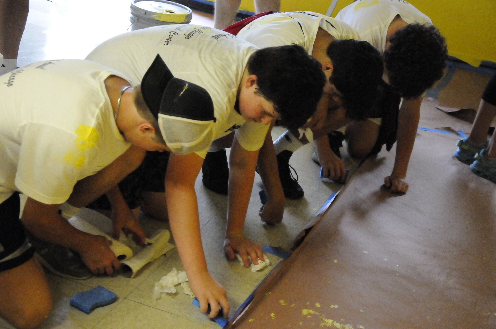 A group of young boys are kneeling on the floor working on a project