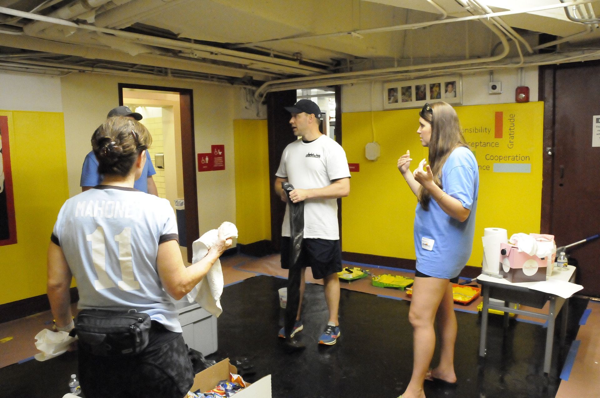 A group of people are standing in a room with yellow walls
