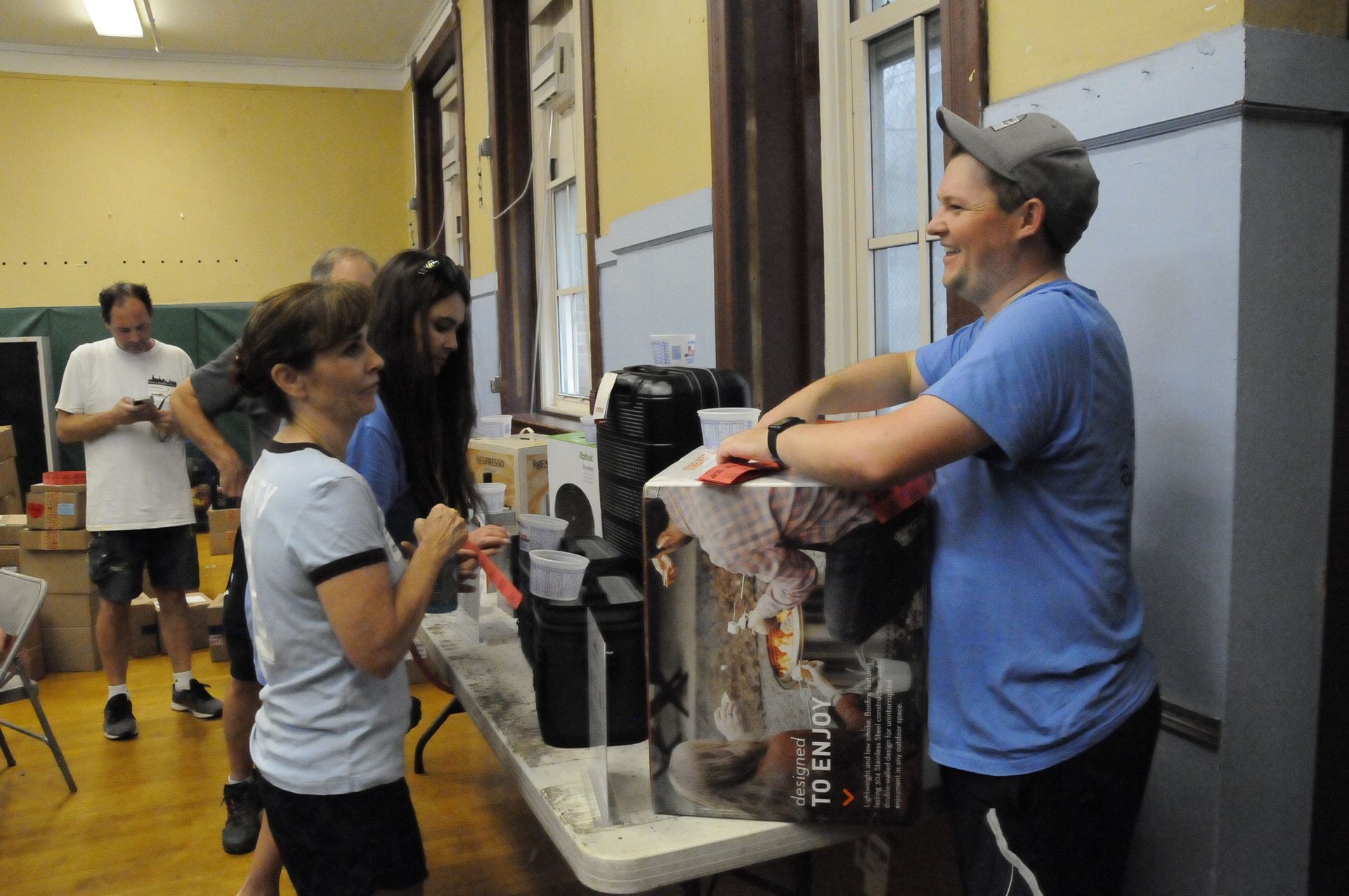 A man in a blue shirt is serving coffee to a group of people