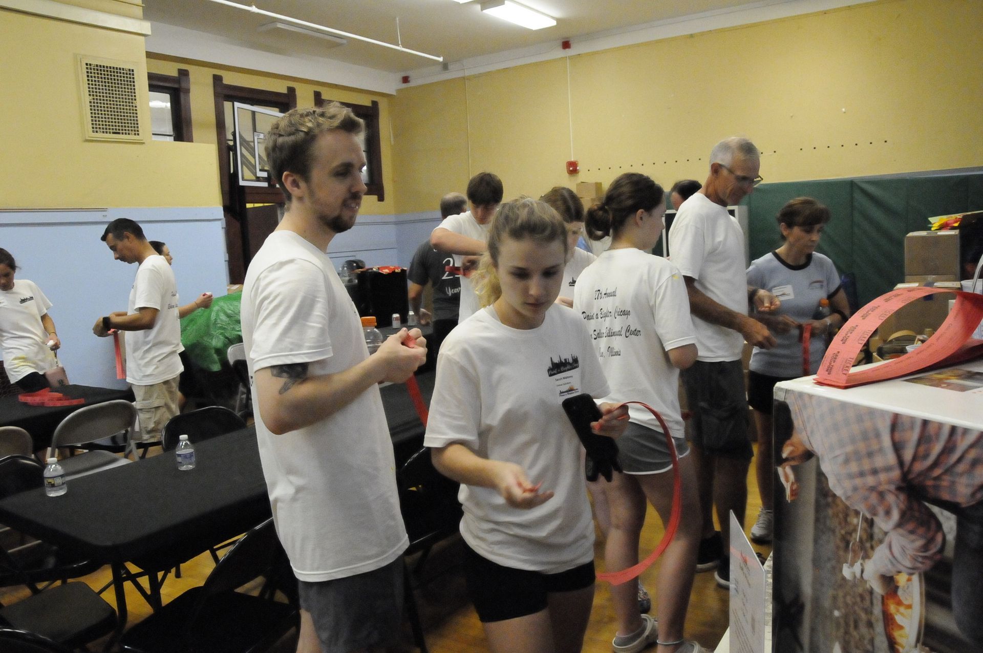 A group of people are standing around tables in a room.