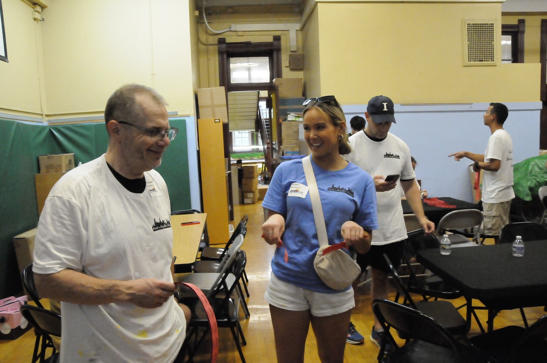 A group of people are standing in a room with tables and chairs