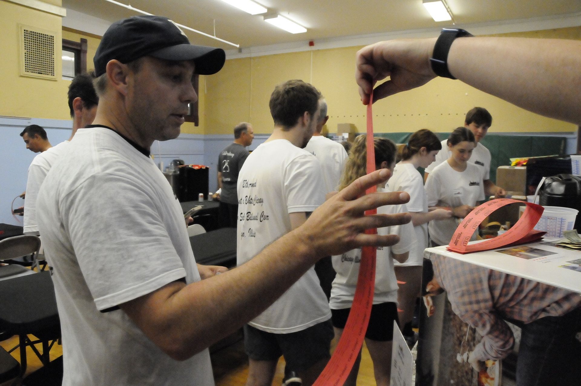 A man wearing a hat is holding a red ribbon