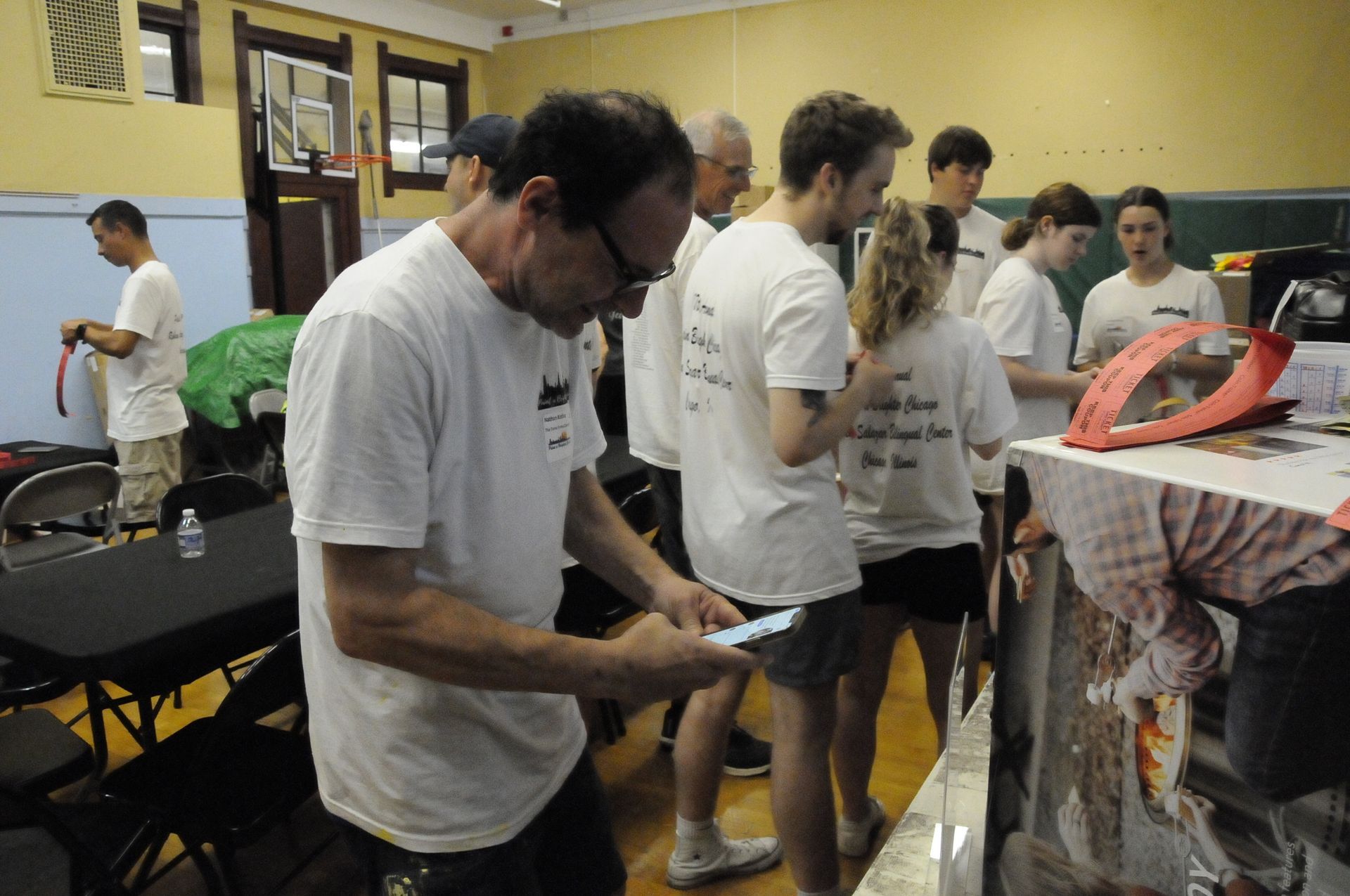 A group of people in white shirts are standing around a table