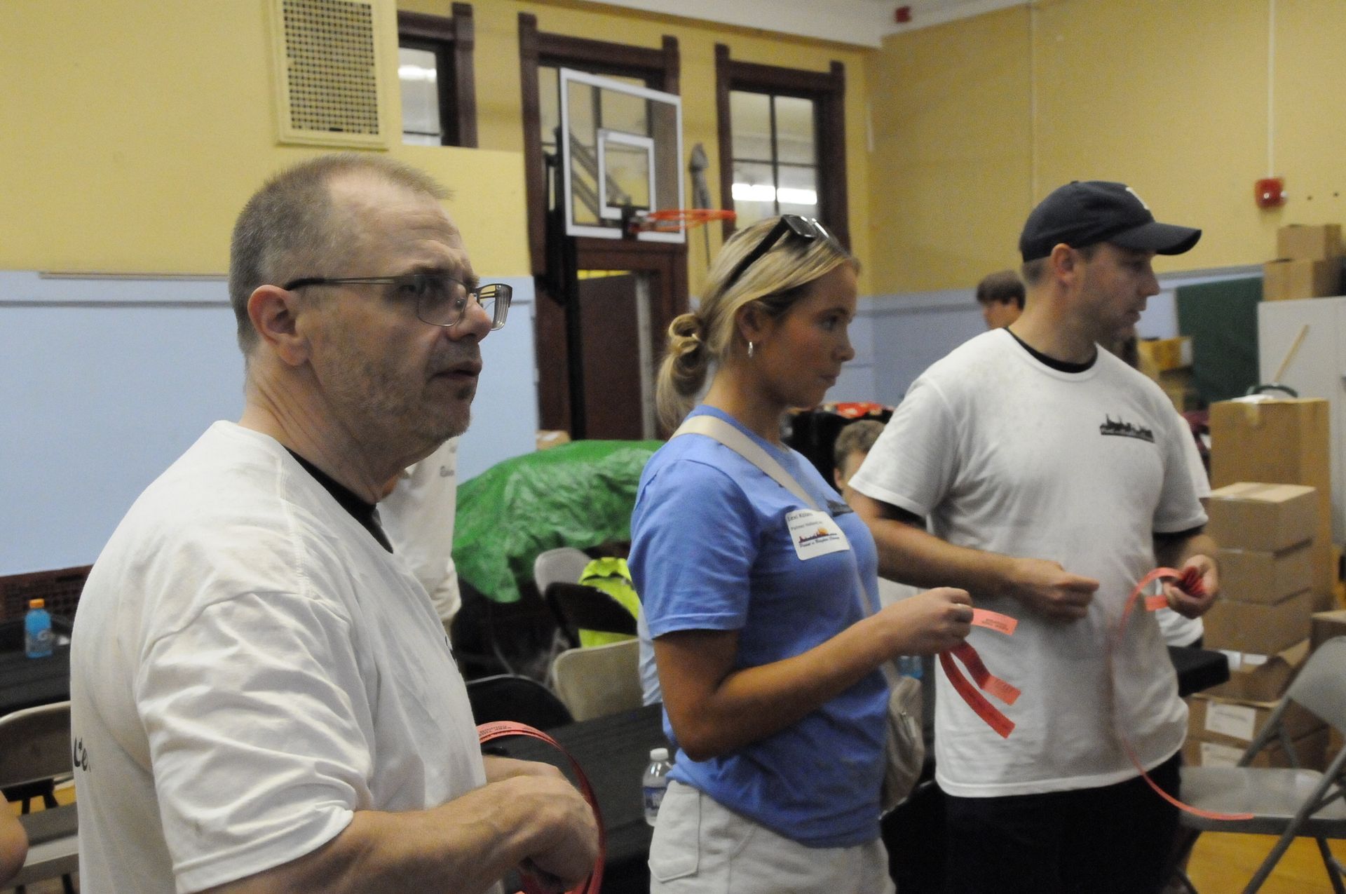 A group of people standing in a room with a basketball hoop in the background