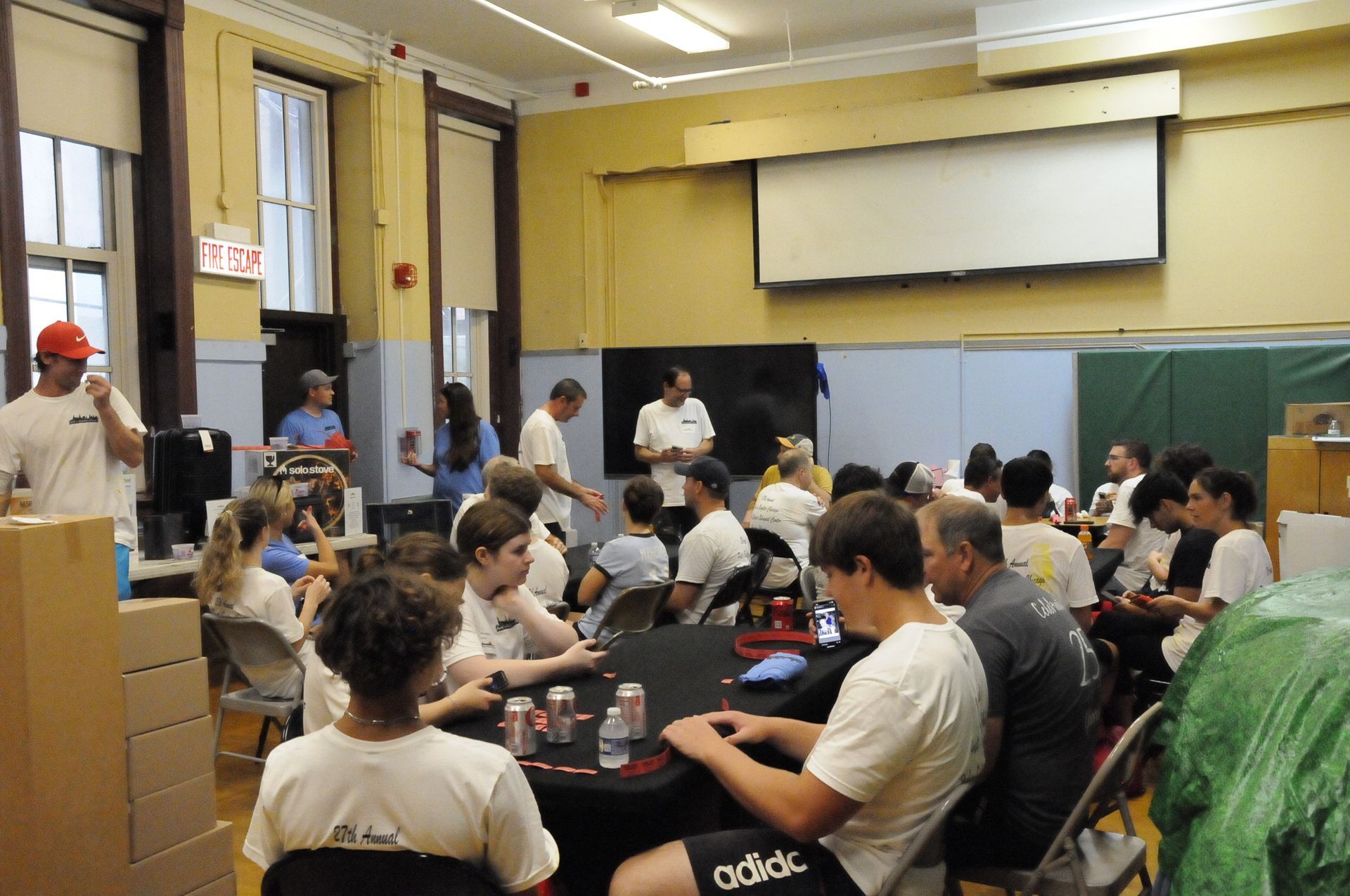 A group of people are sitting around a table in a room with an exit sign above them