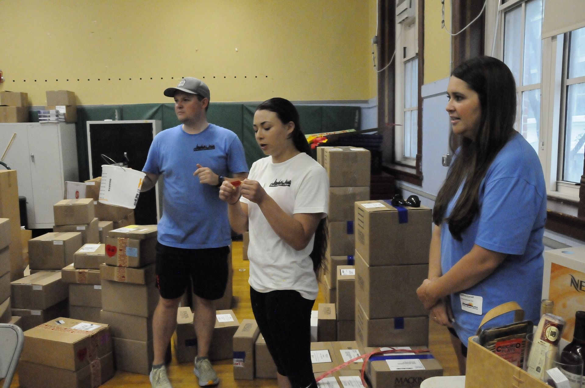 A man and two women are standing in front of a pile of cardboard boxes