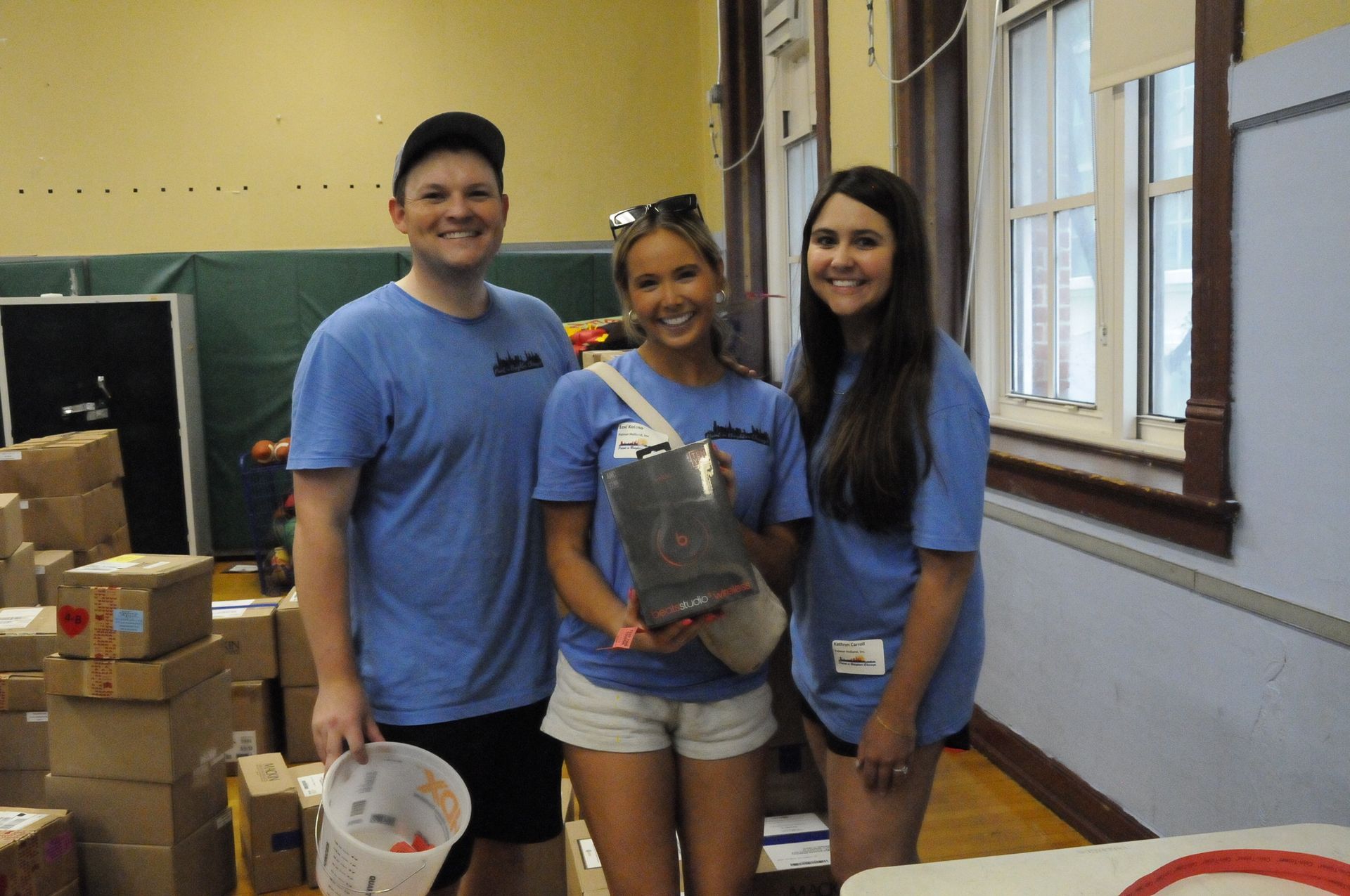 A man and two women in blue shirts are standing next to each other