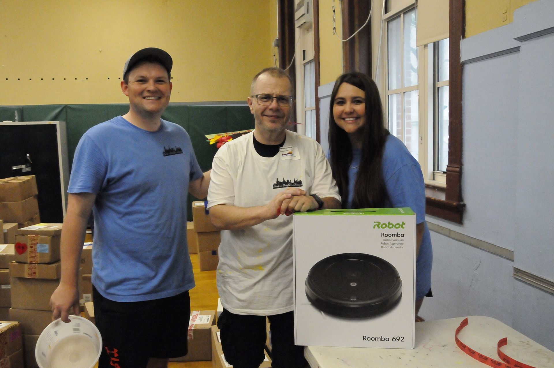 Three people standing next to a robot vacuum cleaner