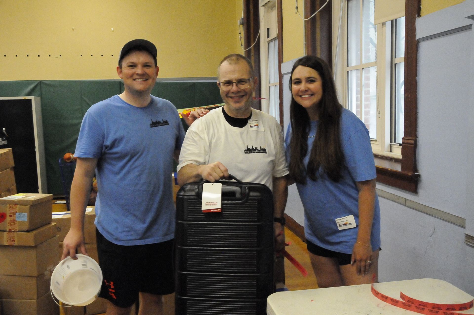 A man and two women are standing next to a suitcase