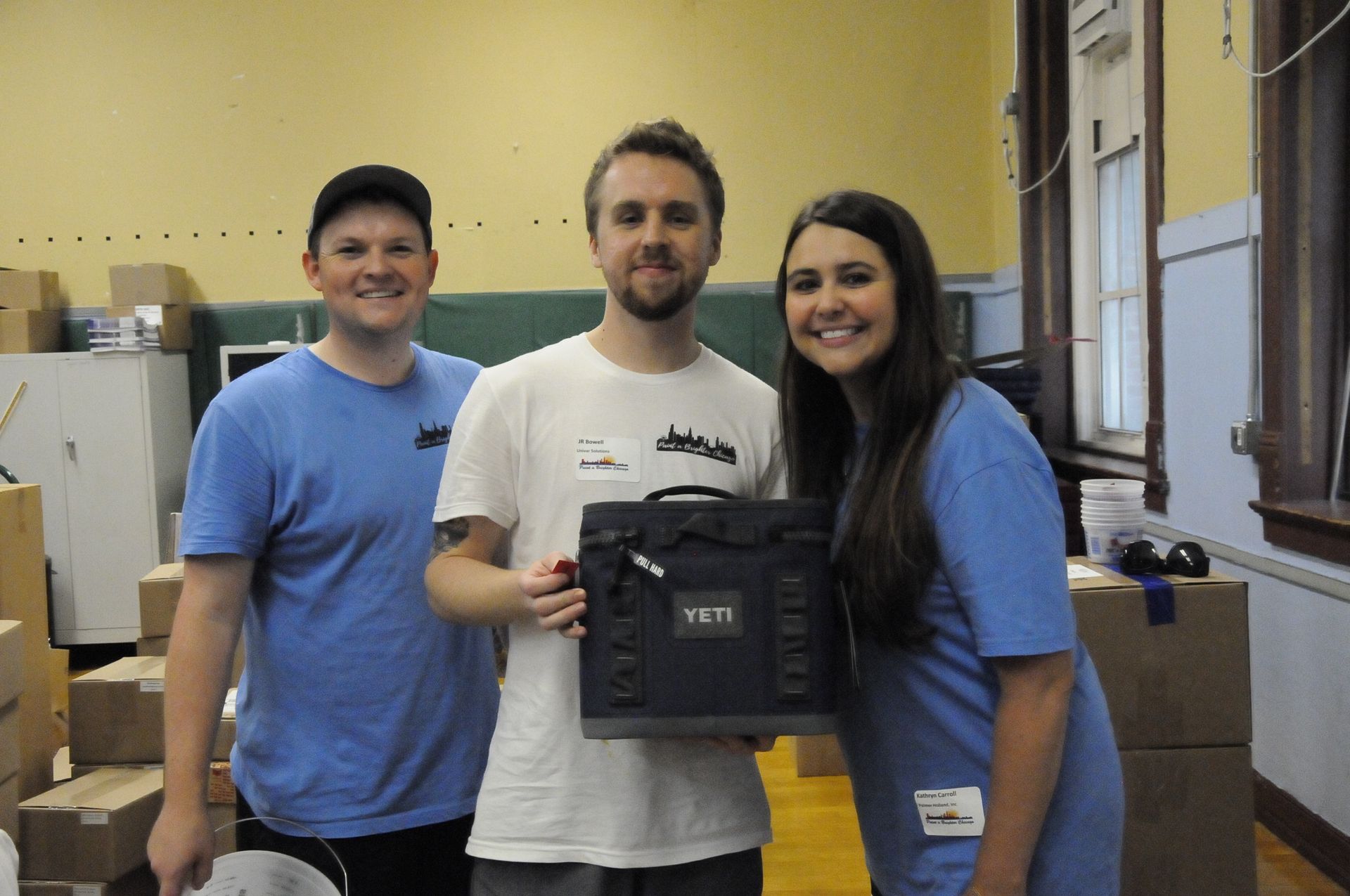 Three people standing next to each other holding a yeti bag
