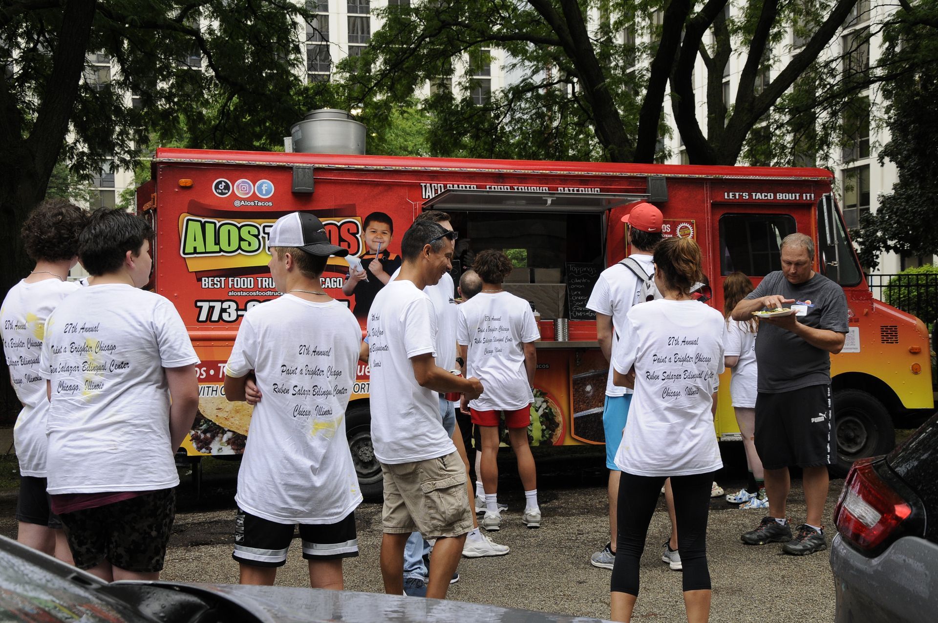 A group of people are standing in front of a food truck that says hugs