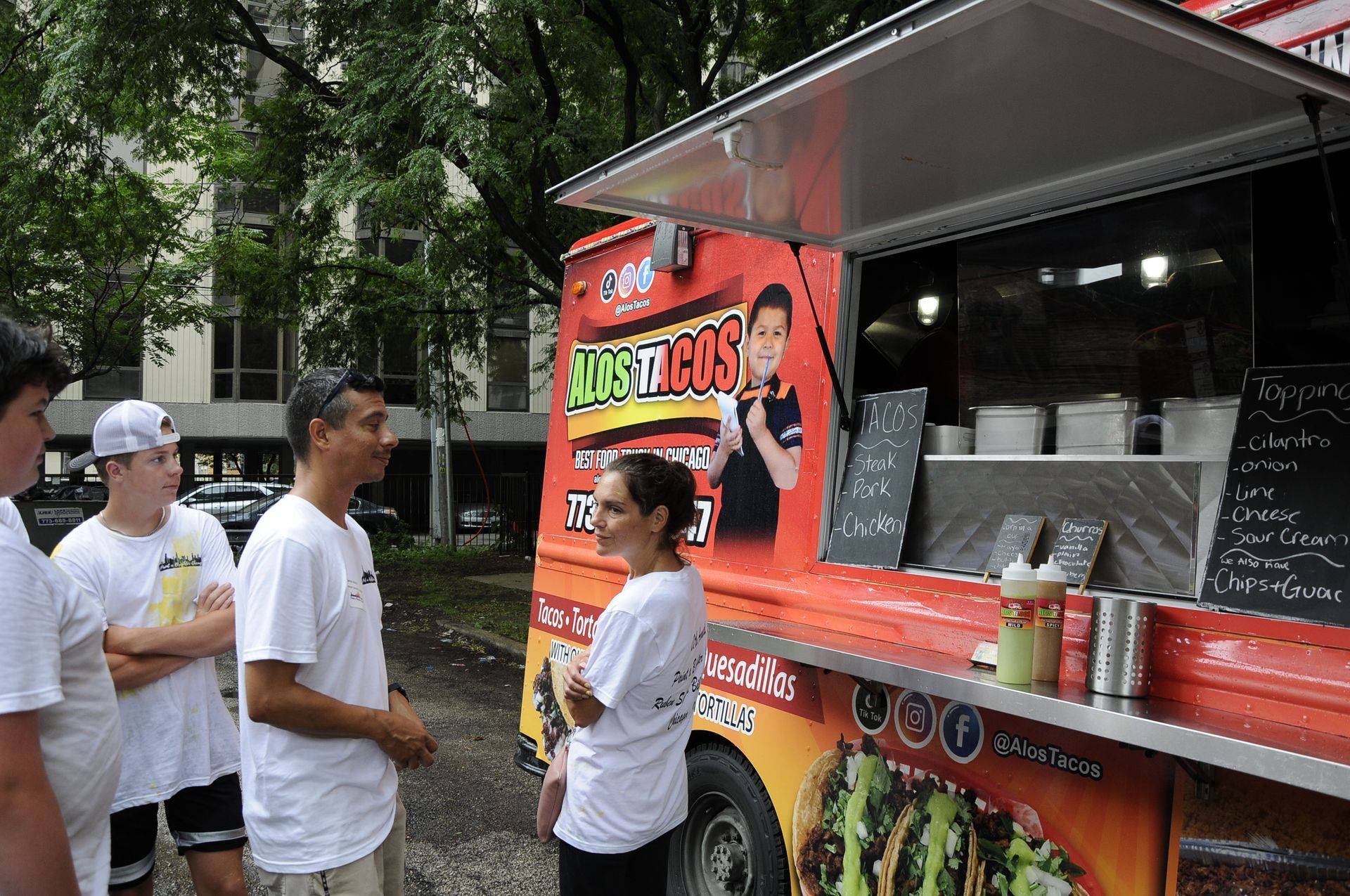 A group of people standing in front of a taco truck