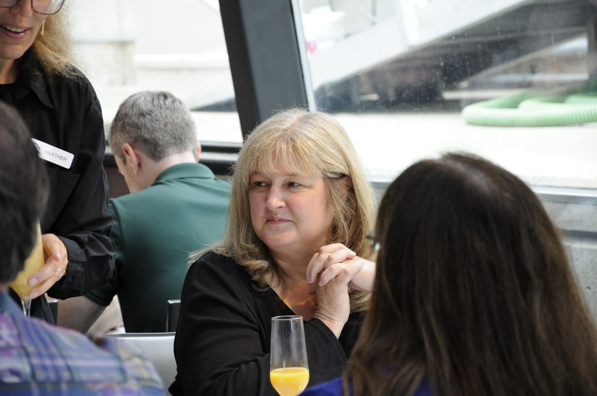 A woman is sitting at a table with a glass of orange juice.