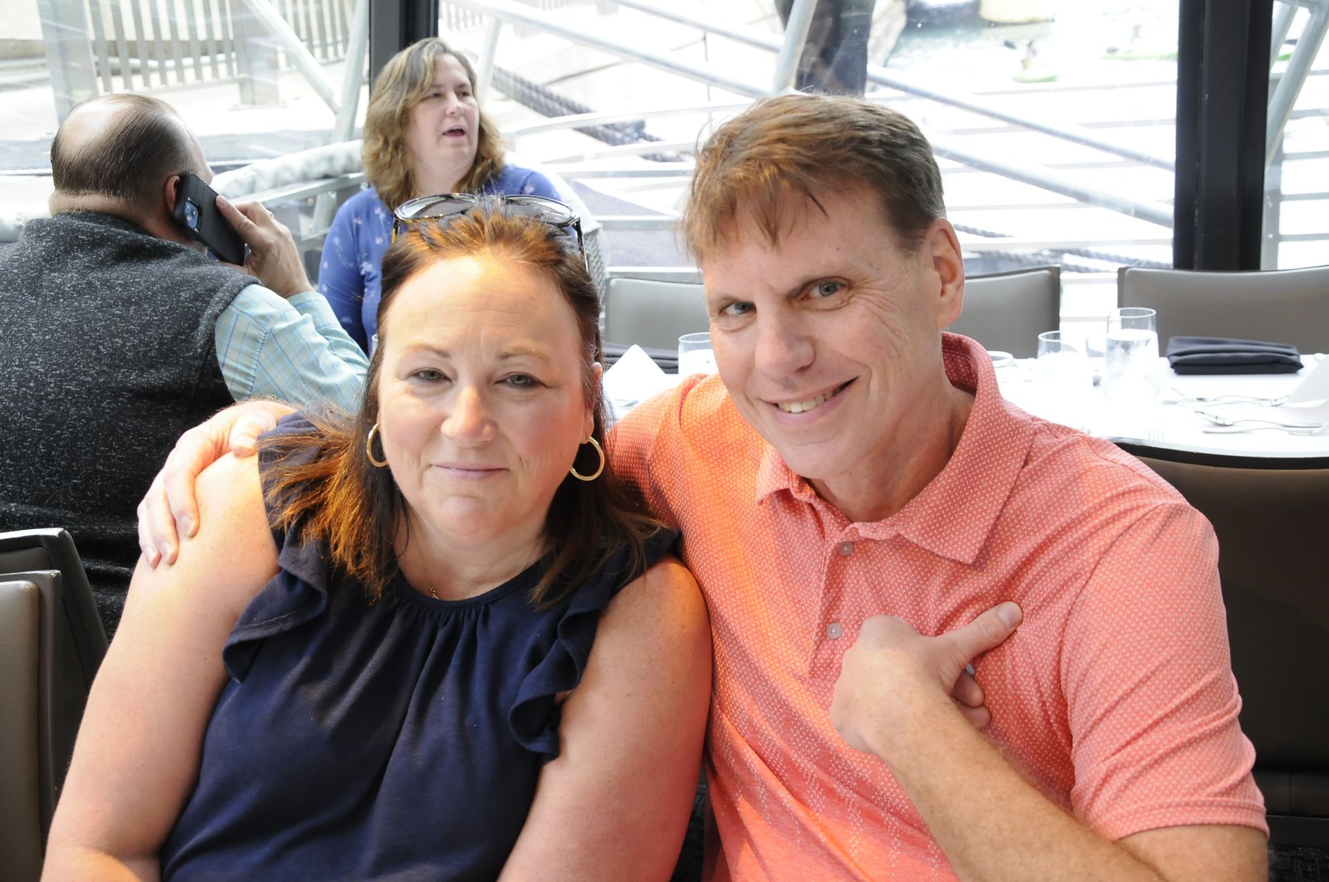 A man and a woman are posing for a picture in a restaurant.