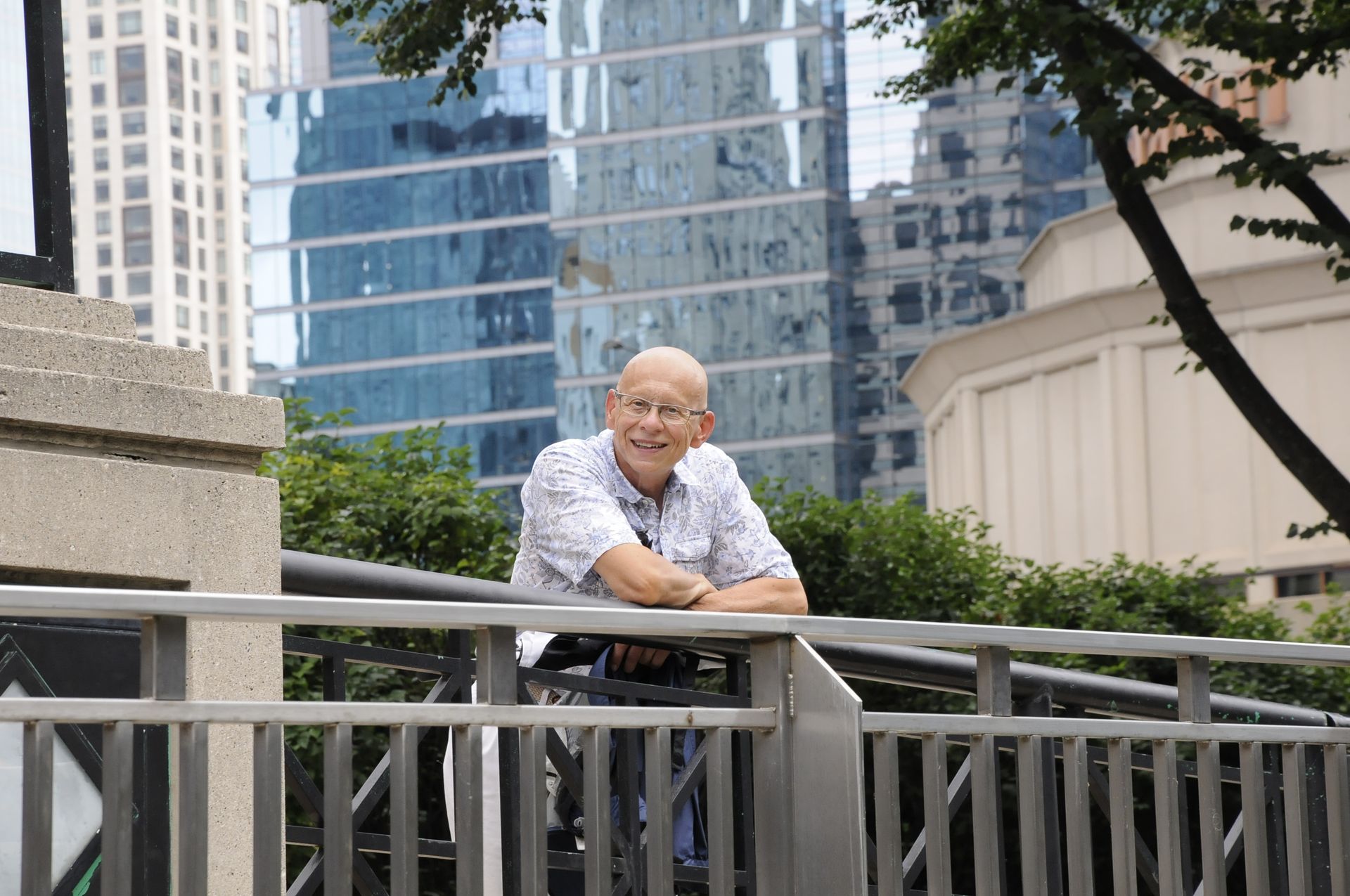 A man leaning on a railing with a city in the background