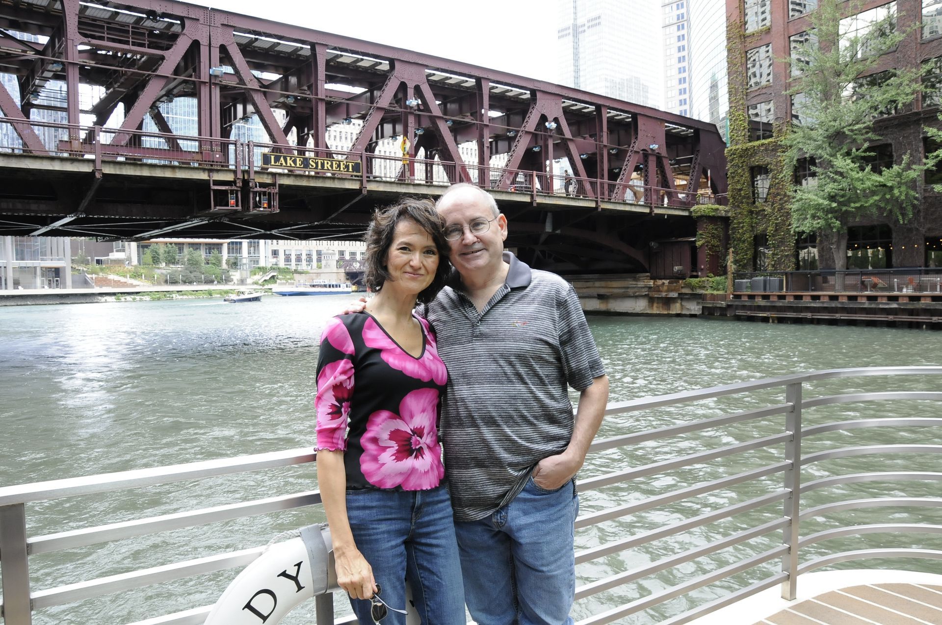 A man and a woman are posing for a picture in front of a bridge