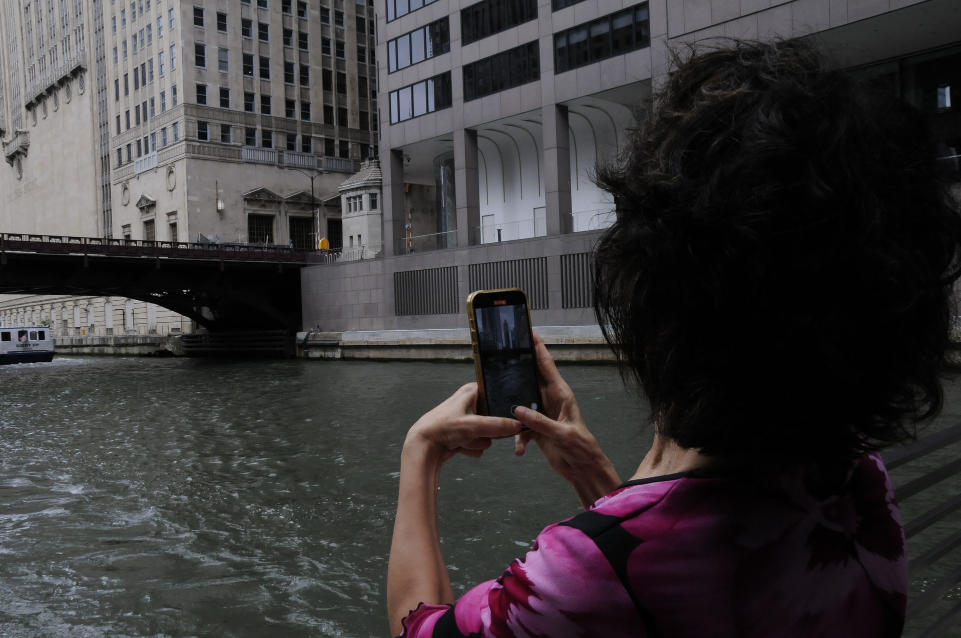 A woman is taking a picture of a bridge over a river
