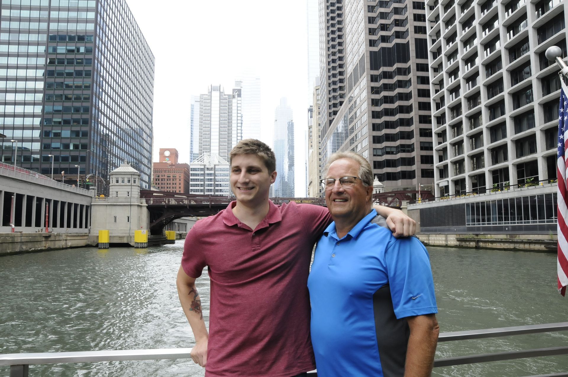 Two men are posing for a picture in front of a river