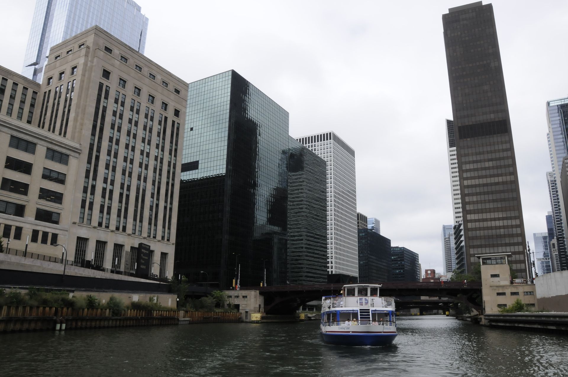 A boat is going down a river in front of tall buildings