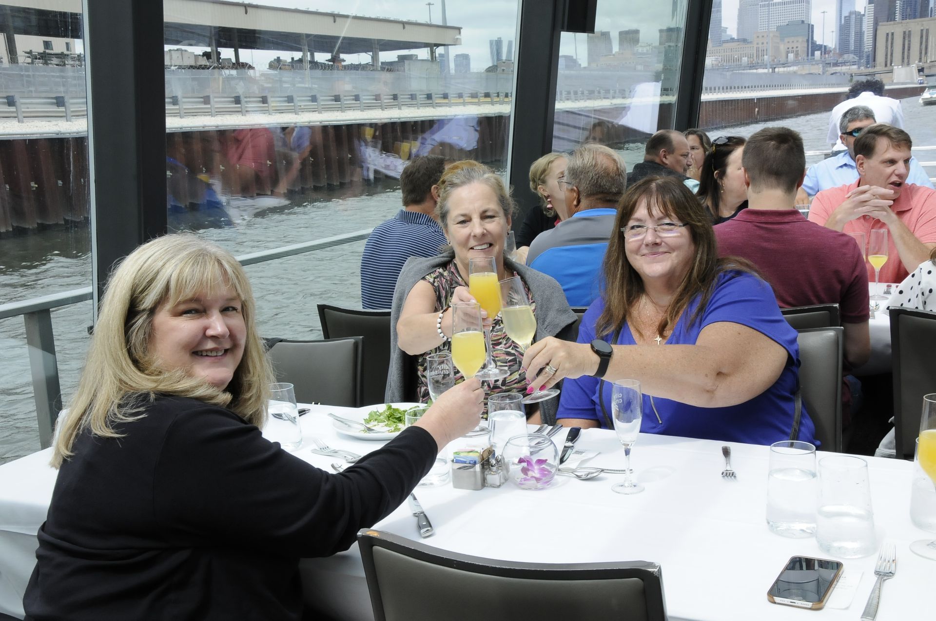A group of people are sitting at a table toasting with drinks.