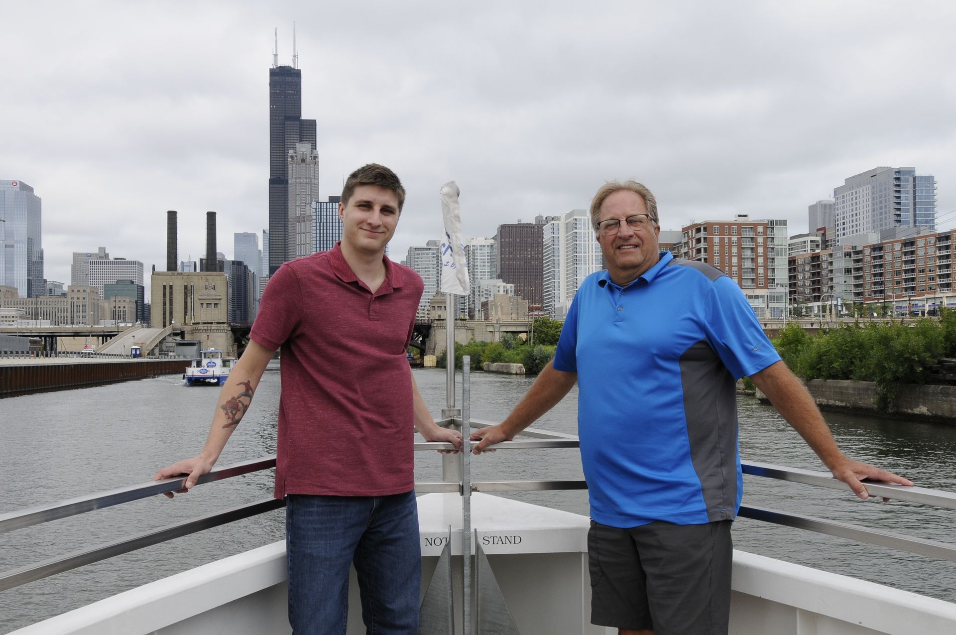 Two men standing on a boat with a city skyline in the background
