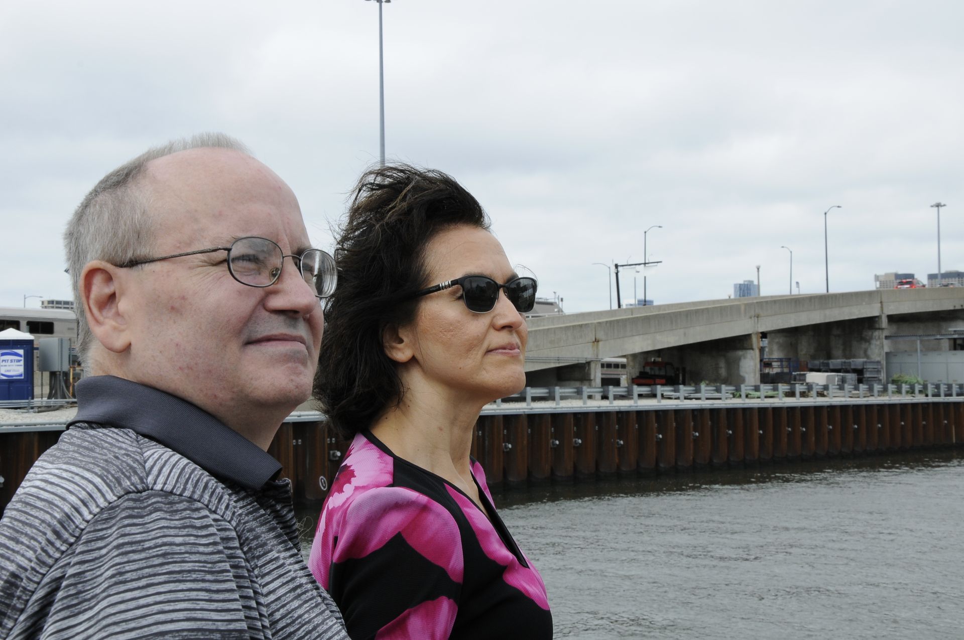 A man and a woman are standing in front of a body of water