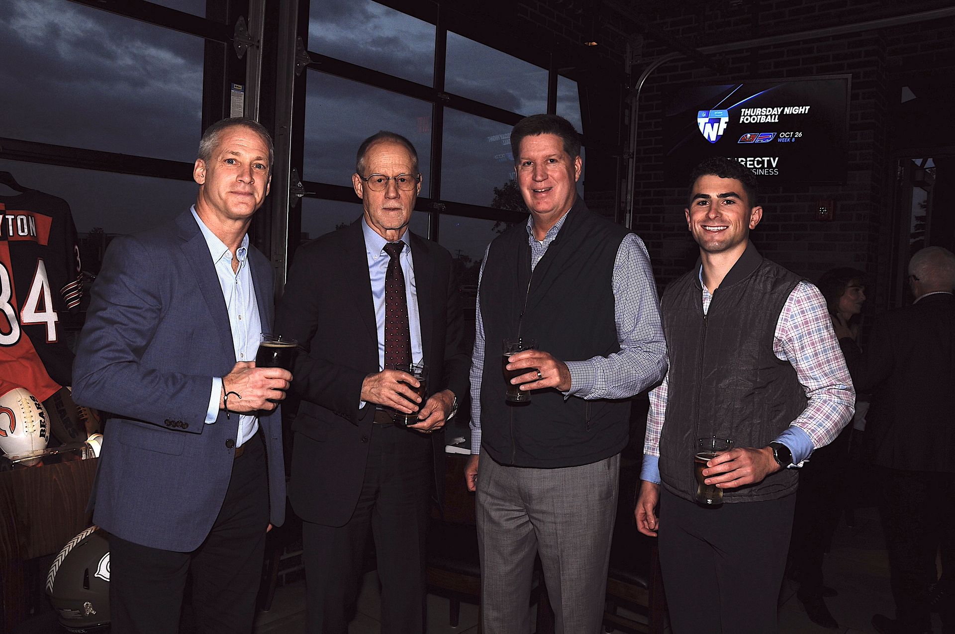 A group of men are standing next to each other holding drinks.