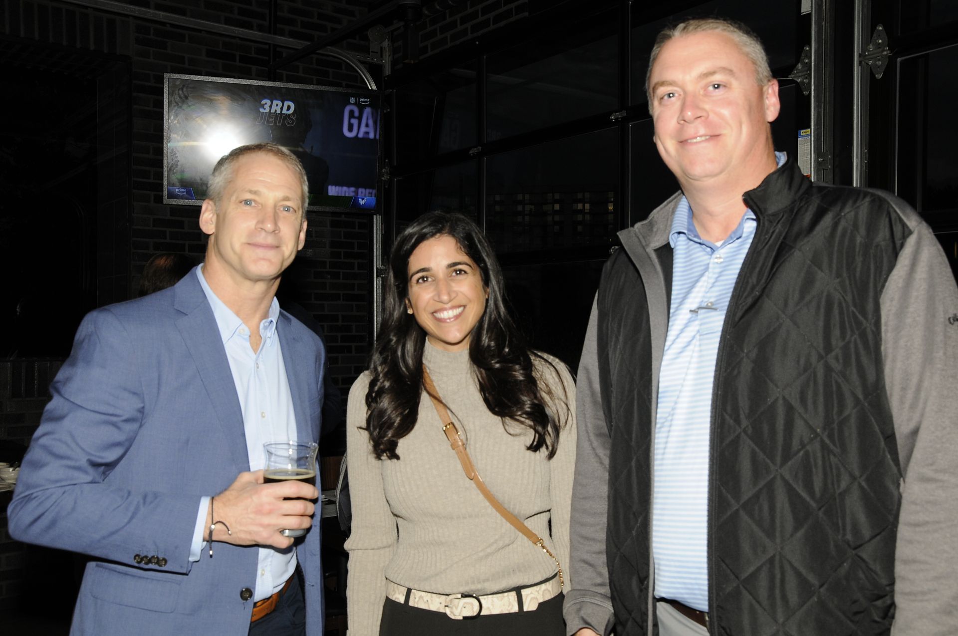 Three people are standing next to each other in a dark room.