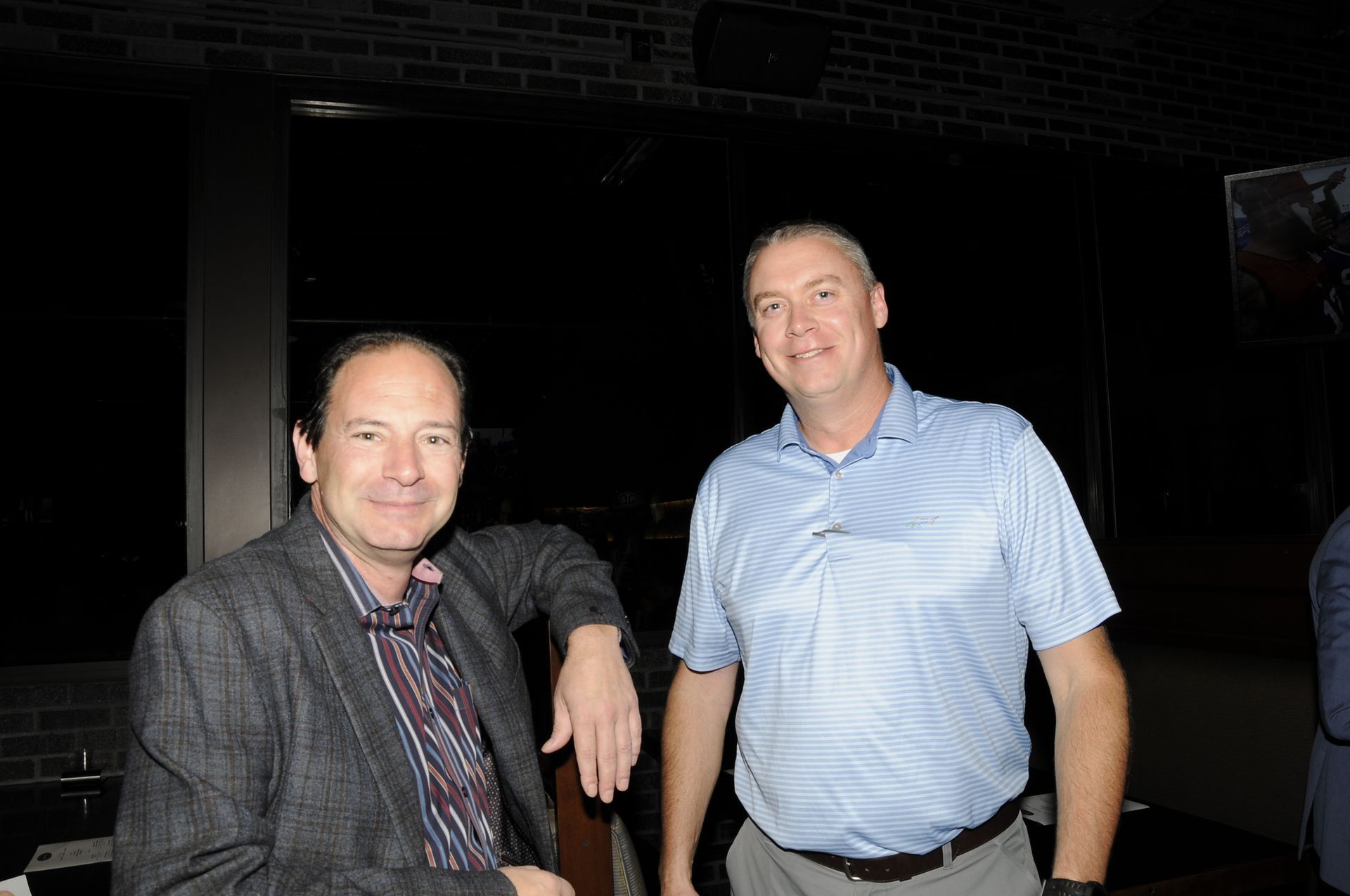 Two men are posing for a picture in a dark room.