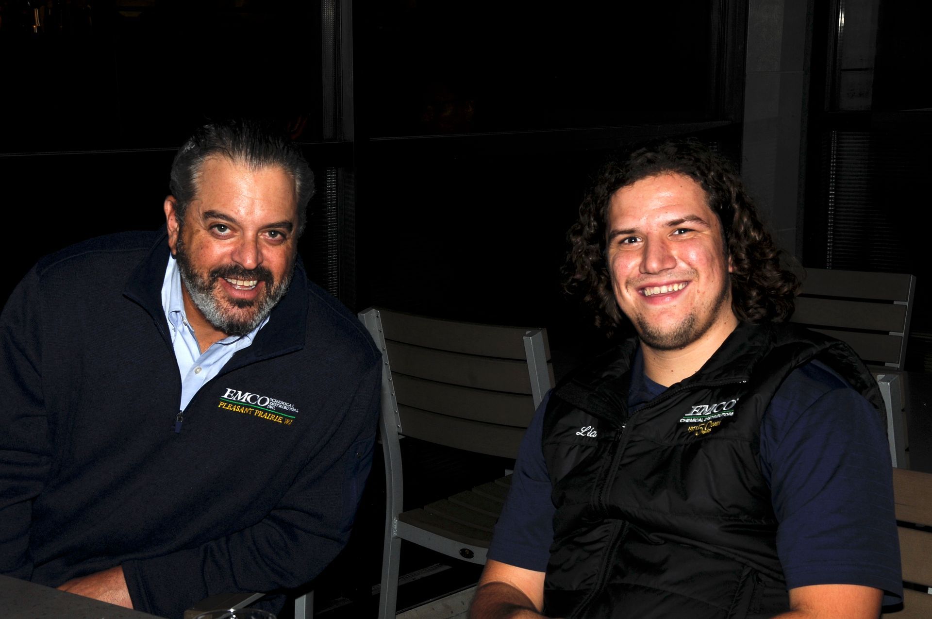 Two men are sitting next to each other at a table and smiling.