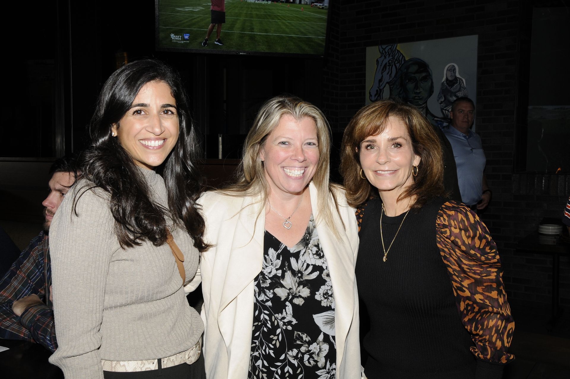 Three women are posing for a picture together in a dark room.