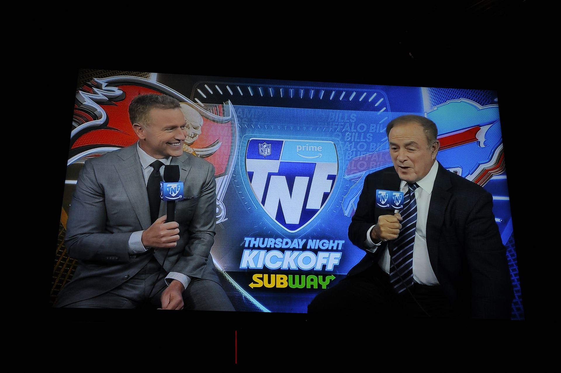 Two men are sitting in front of a screen that says tnf kickoff subway