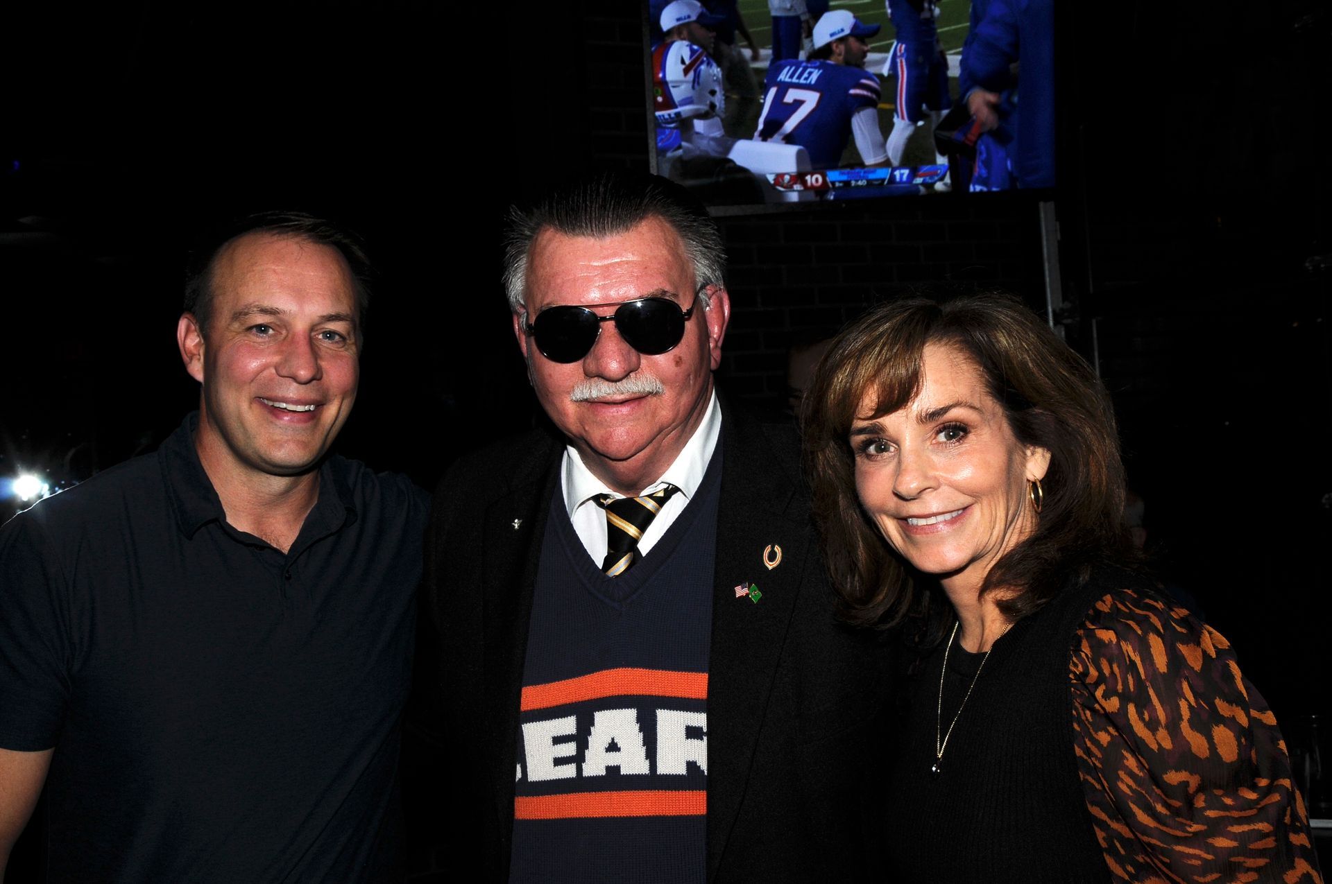 A man wearing a shirt that says ear is standing next to two other people